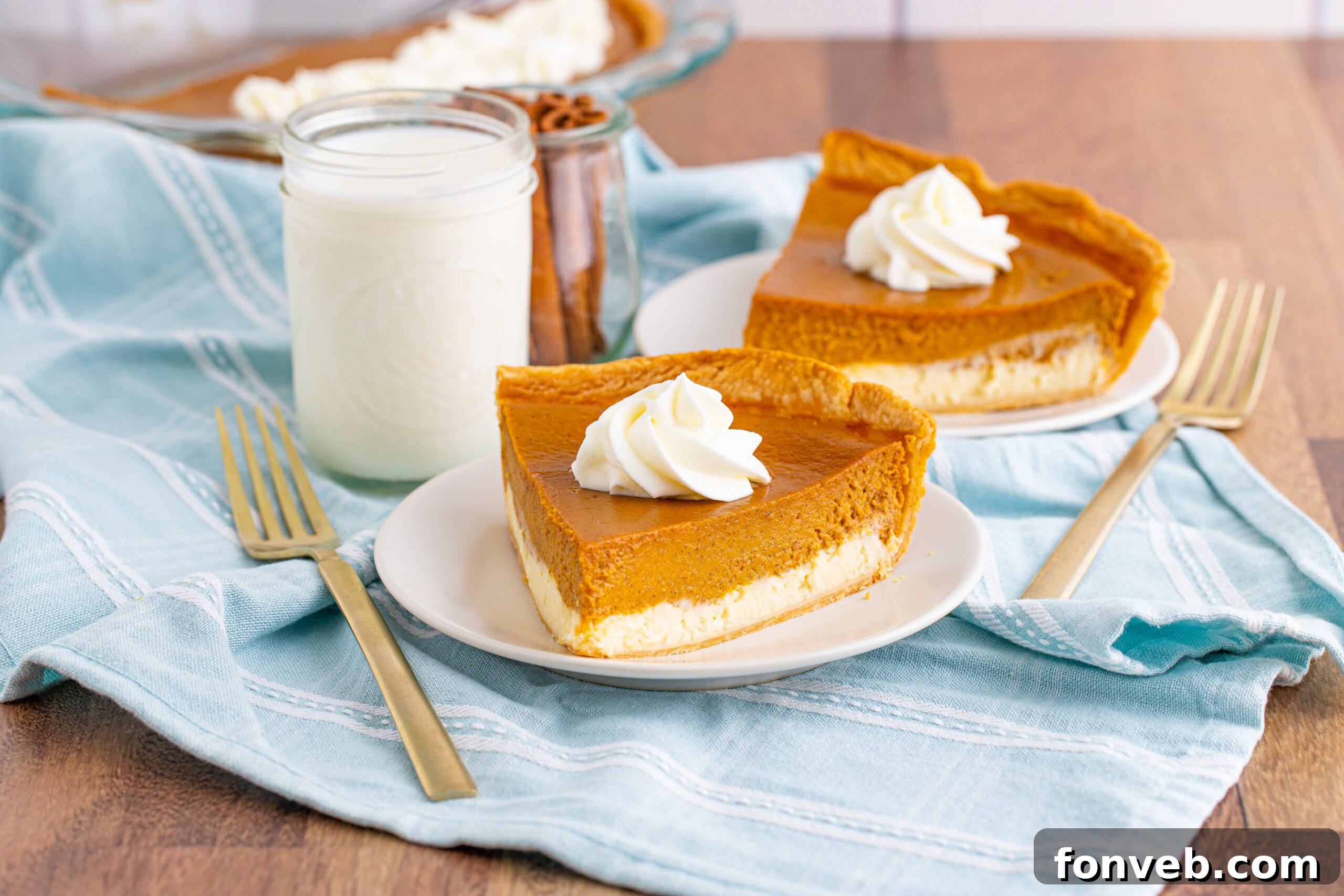 Two slices of Pumpkin Pie Cheesecake on white plates, with a soft focus on the background