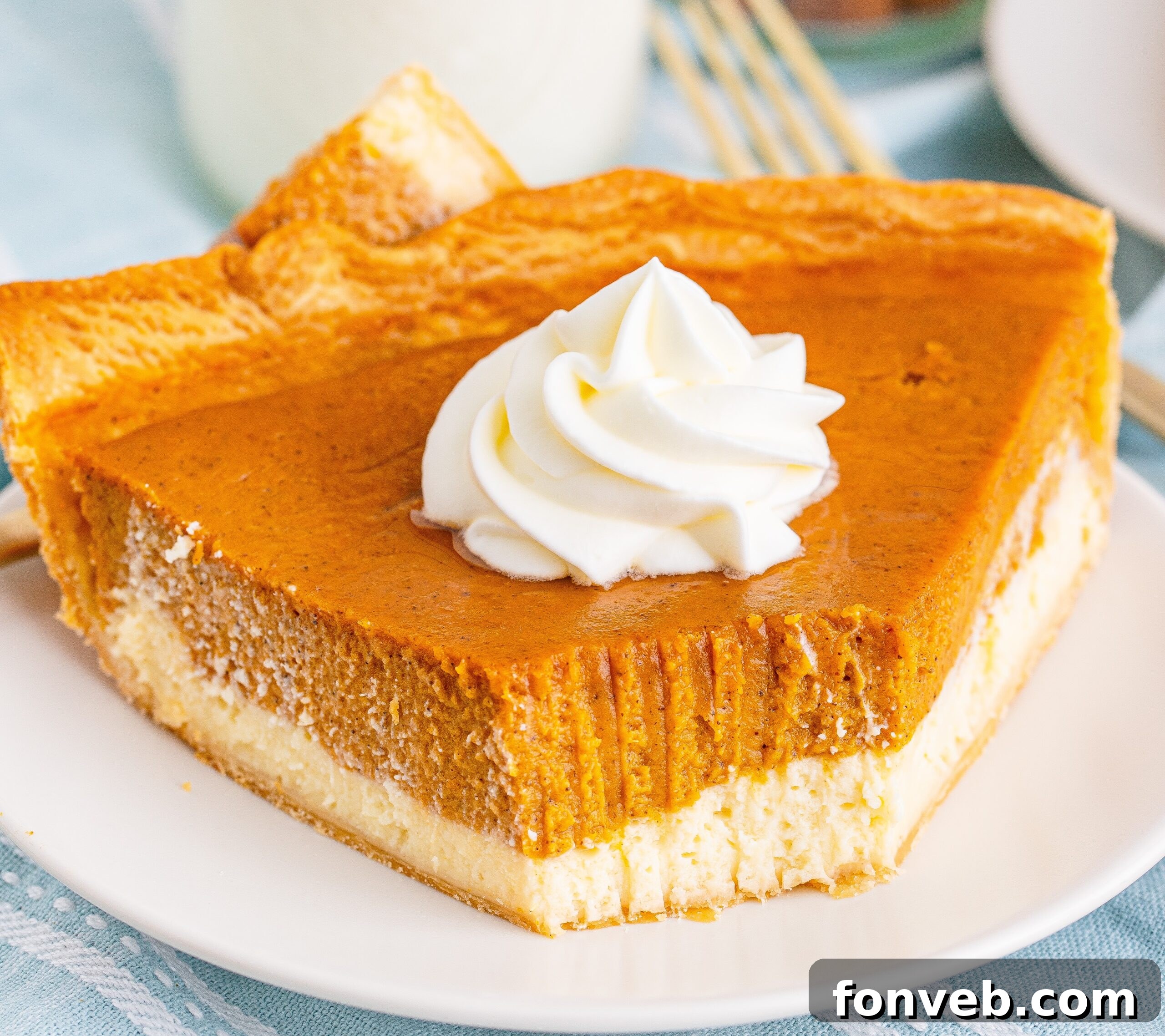 A slice of Pumpkin Pie Cheesecake on a white plate with a bite taken out, showing the layers and creamy texture