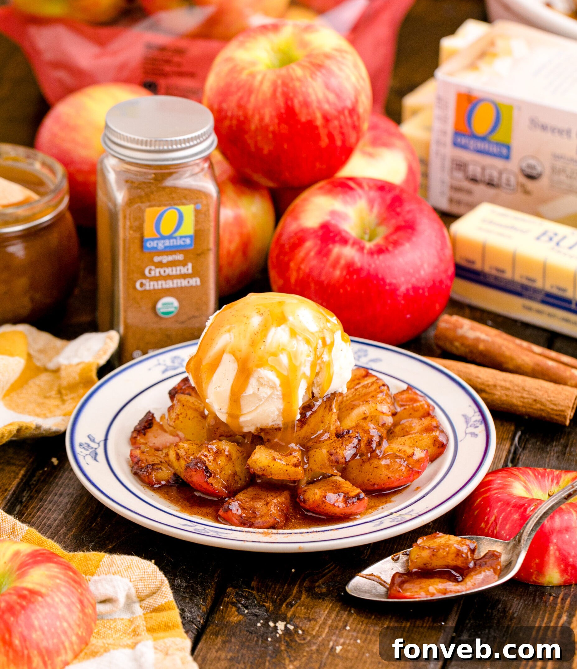 Oven Baked Bloomin Apples on a white plate topped with ice cream on a wood table with apples in the background