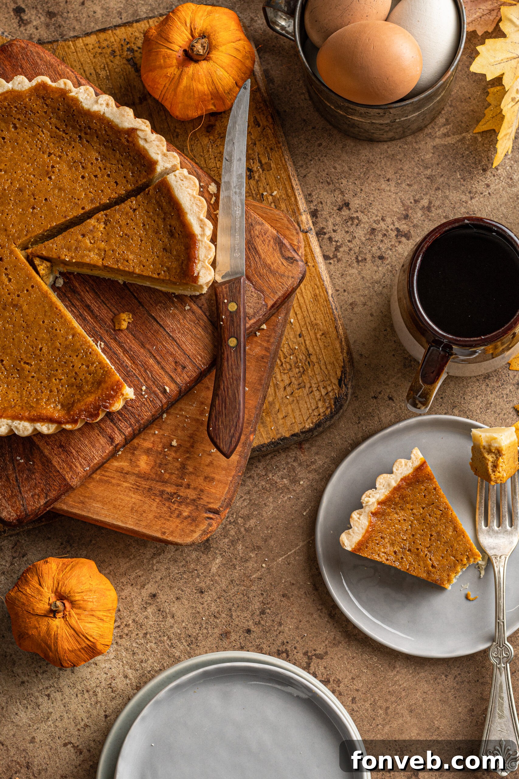 Overhead shot of a slice of Pumpkin Pie Tart on a gray plate with a mug of coffee in the background, creating a cozy atmosphere