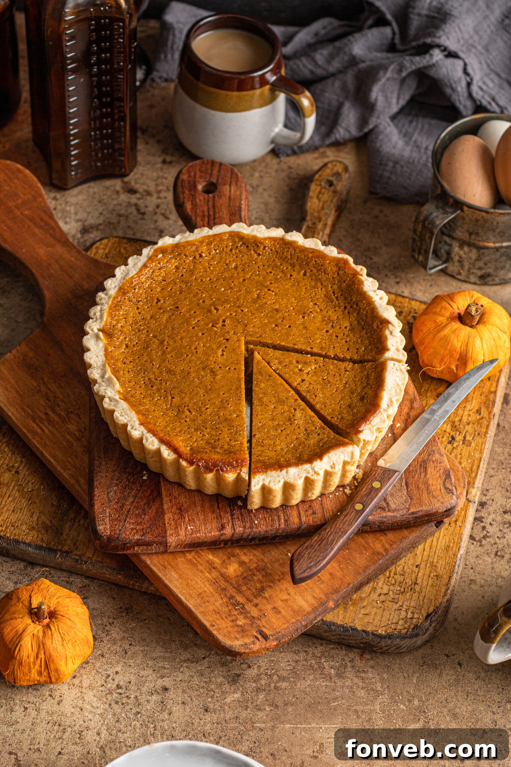 Pumpkin Pie Tart artfully arranged on a wooden cutting board with a mug of steaming coffee and small decorative pumpkins for a cozy fall scene
