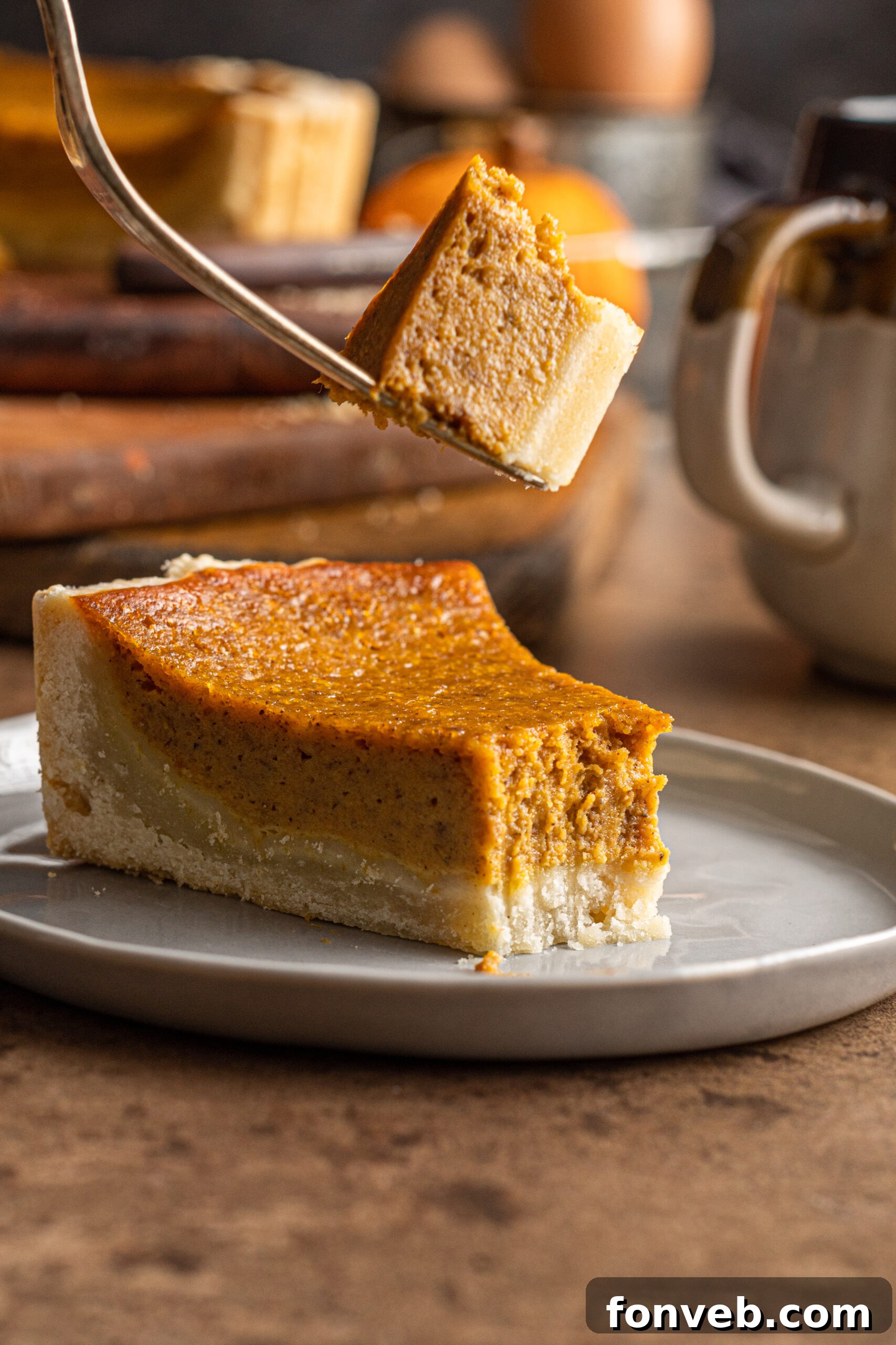 A fork lifting a bite of Pumpkin Pie Tart from a slice on a plate