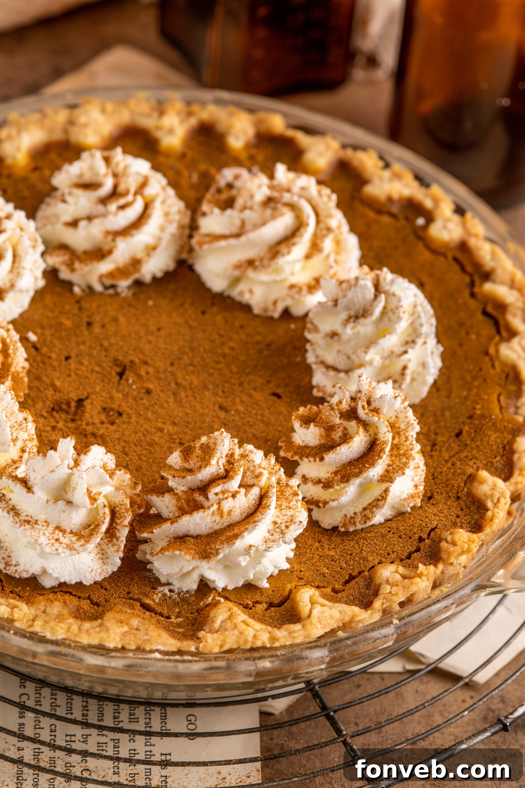 Velvet Pumpkin Dream Pie 11 A full Pumpkin Custard Pie, adorned with charming dollops of freshly whipped cream, presenting a delightful and inviting dessert.
