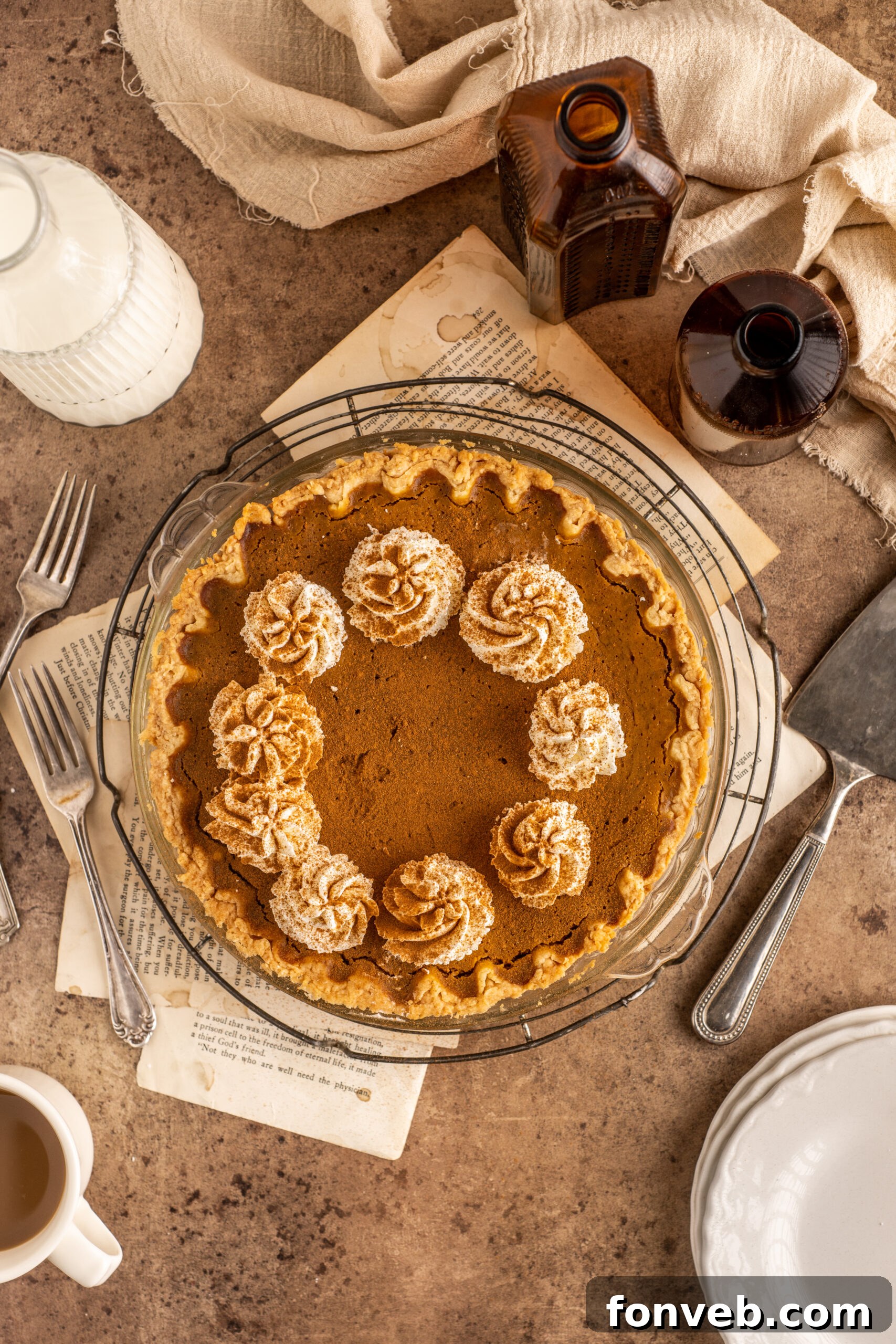 Velvet Pumpkin Dream Pie 4 A close-up shot of a whole Pumpkin Custard Pie, glistening with a creamy texture, topped generously with fluffy whipped cream in a clear glass pie dish.