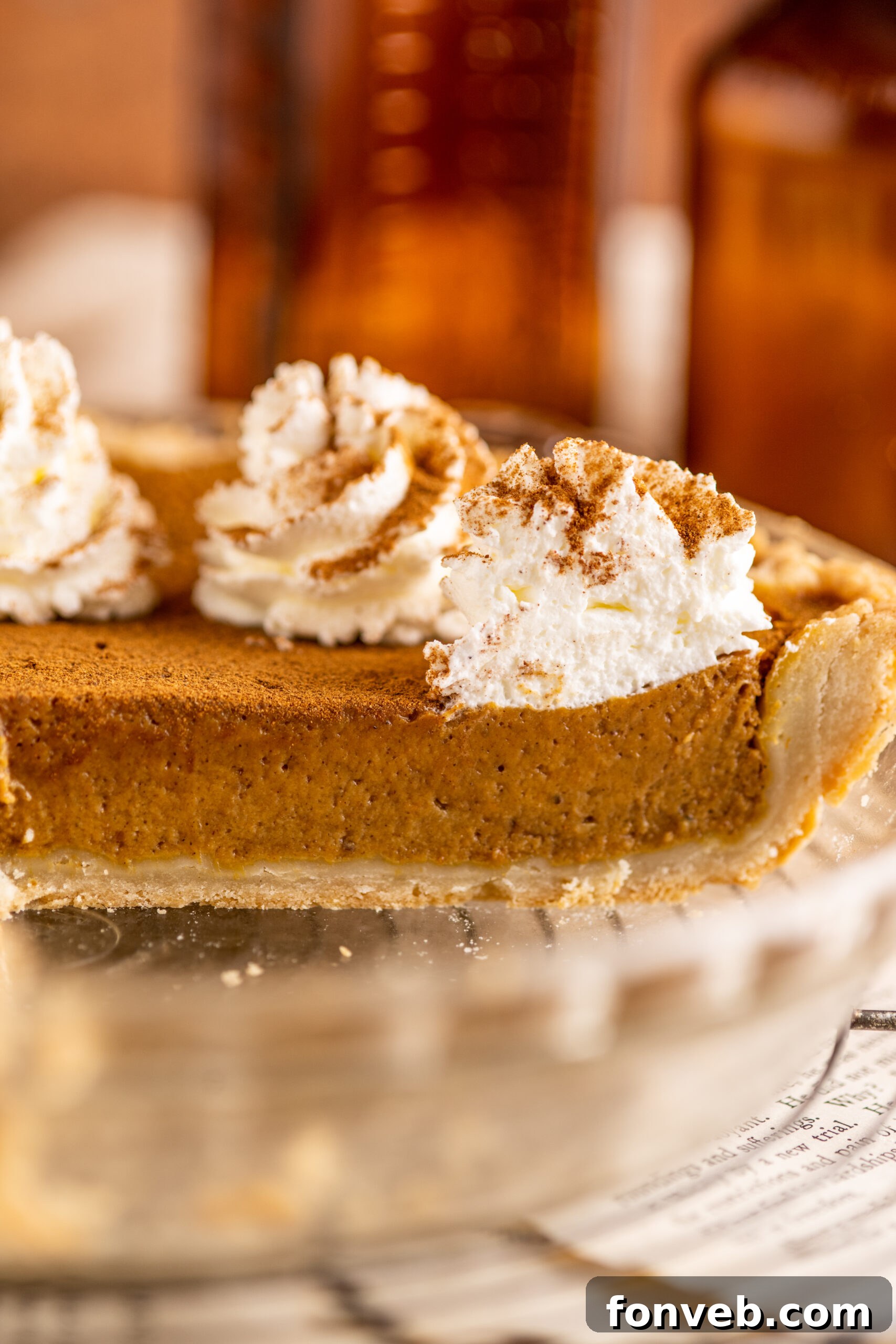 Velvet Pumpkin Dream Pie 9 A full Pumpkin Custard Pie resting in a clear glass pie dish, presenting its smooth, inviting surface.