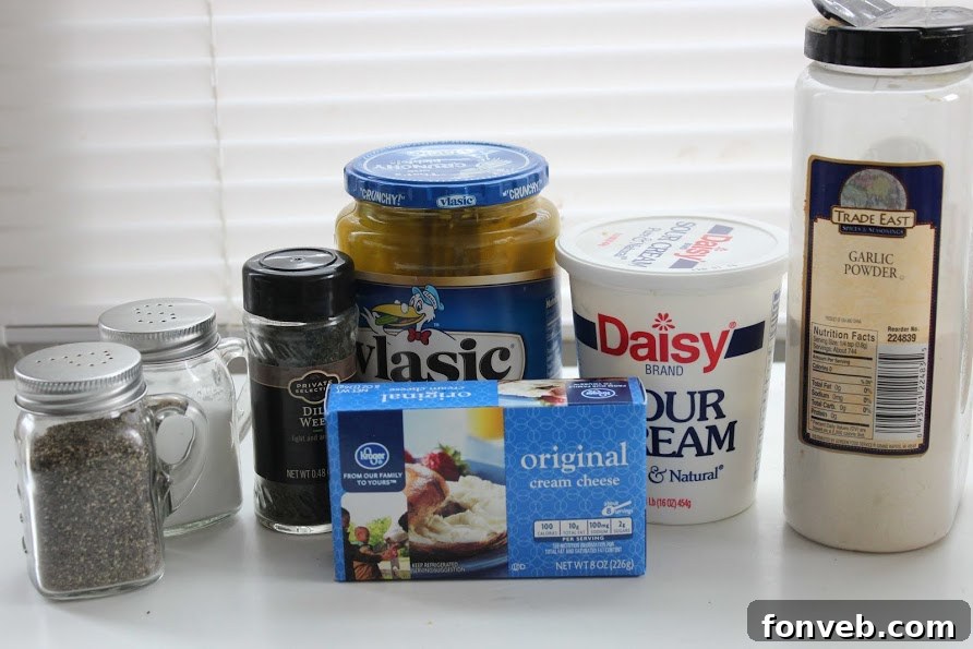 Close-up of fresh ingredients for Dill Pickle Dip, including softened cream cheese, sour cream, and crisp dill pickles.