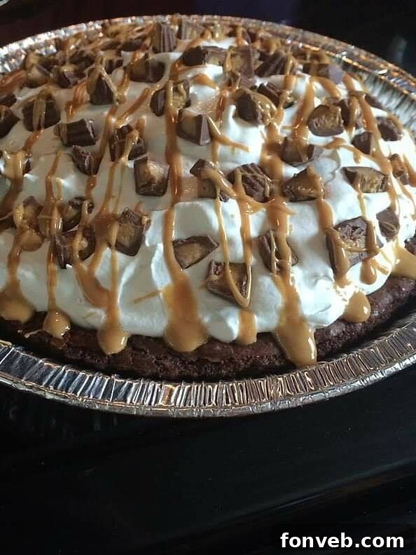 Peanut Butter Brownie Pie garnished with hot fudge, peanut butter drizzle, and chopped nuts