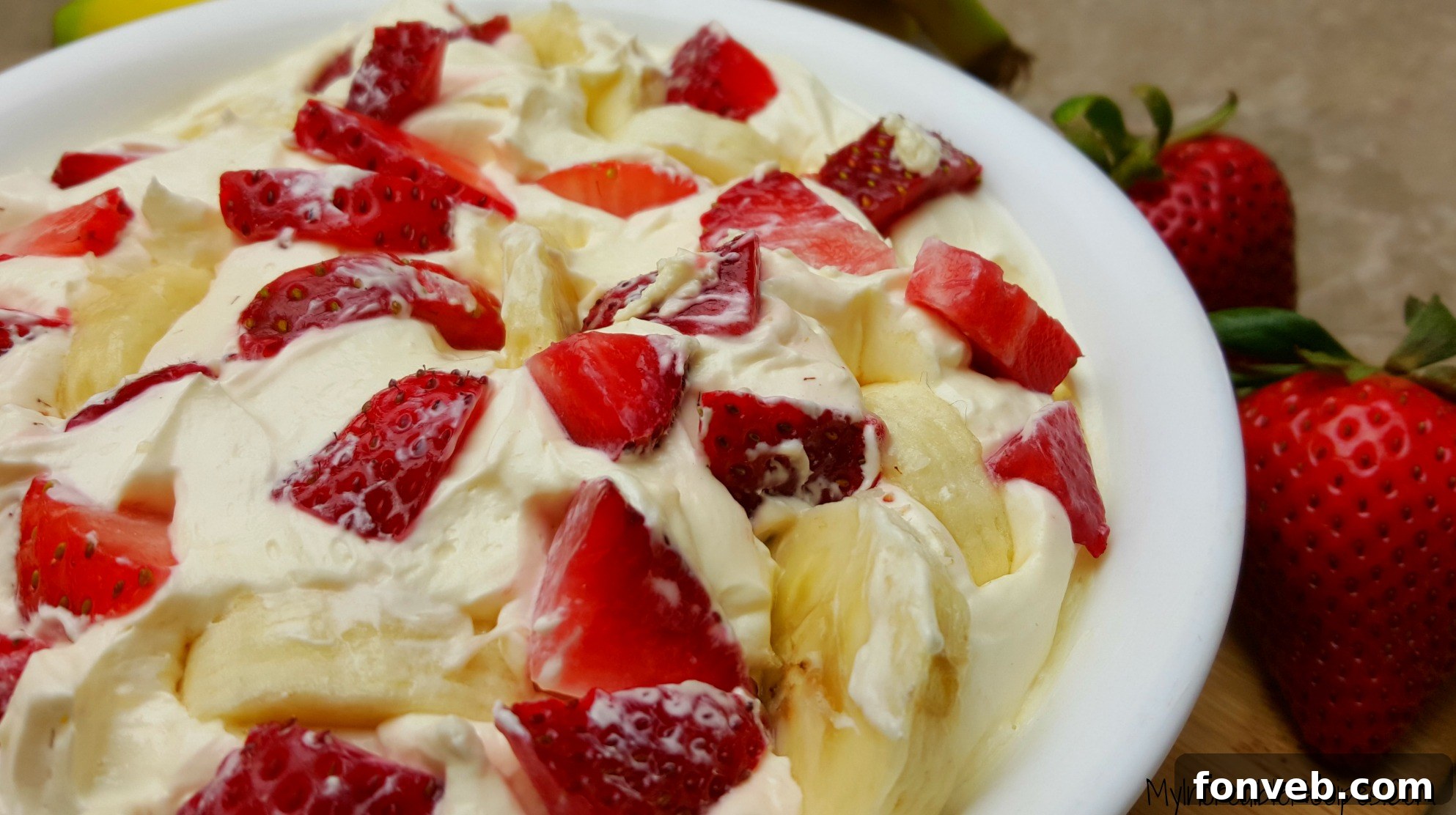 Strawberry Banana Cheesecake Delight 6 A vibrant mix of fruits, including strawberries and bananas, coated in a creamy cheesecake dip.