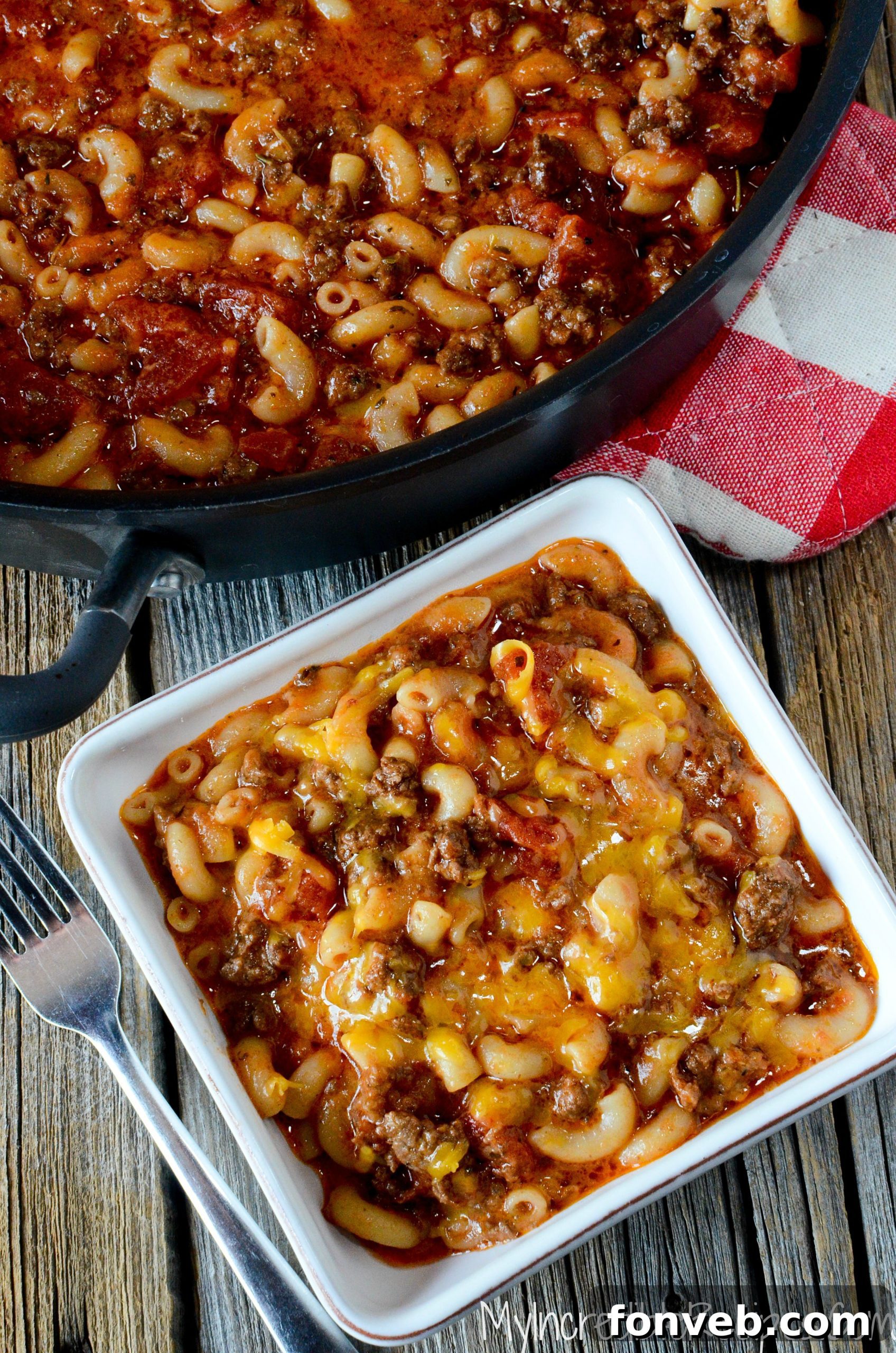 Old Fashioned Goulash simmering in a large black pot on a wooden table, creating a warm and inviting scene.