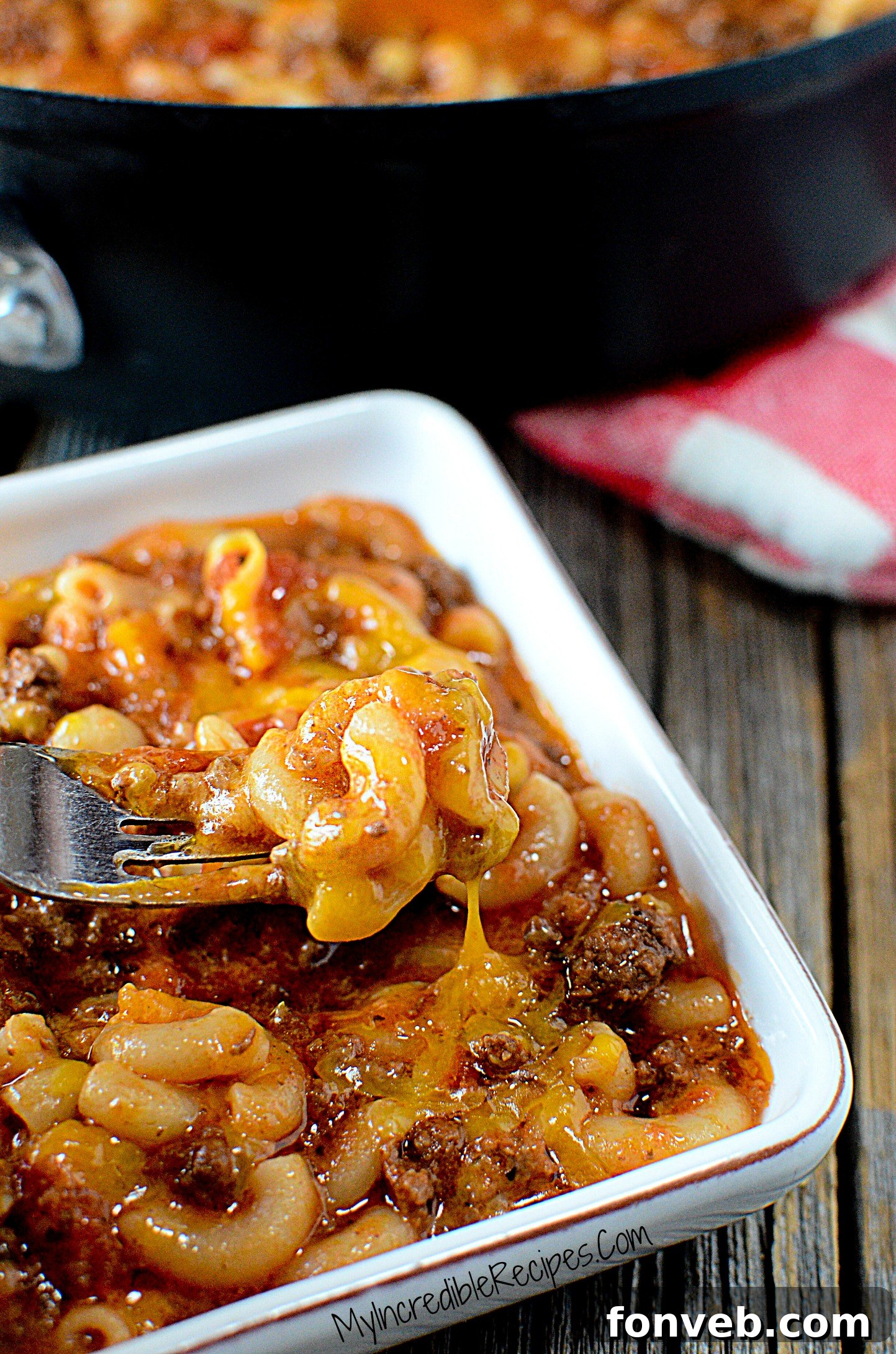 A white bowl filled with Old Fashioned Goulash, with a fork lifting a savory bite, showcasing the texture of the pasta and meat.