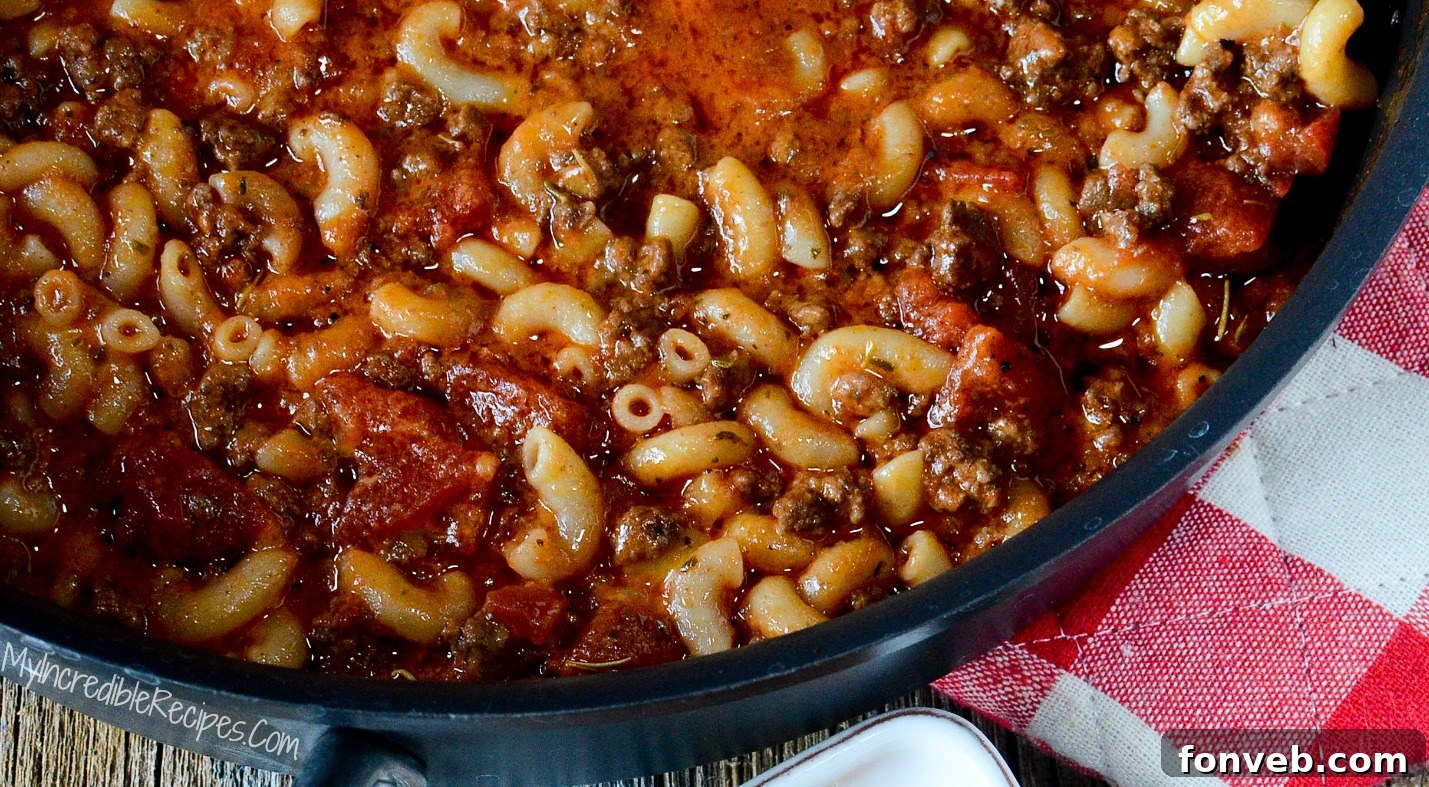 A vibrant pot of Old Fashioned Goulash, rich in color and texture, on a simple backdrop.