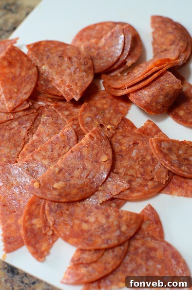 A bowl of fresh Italian Pizza Pasta Salad with a focus on cubed provolone and mozzarella cheeses and sliced pepperoni