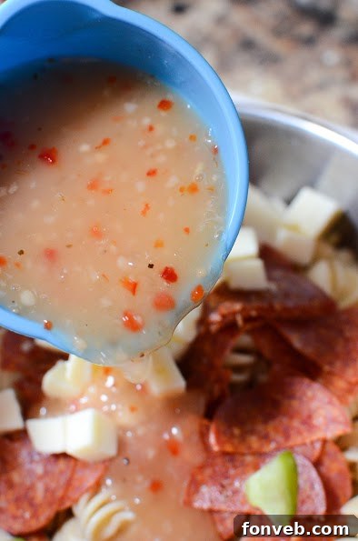 Close-up on a portion of Italian Pizza Pasta Salad, focusing on the pepperoni slices and cheese cubes mixed with pasta