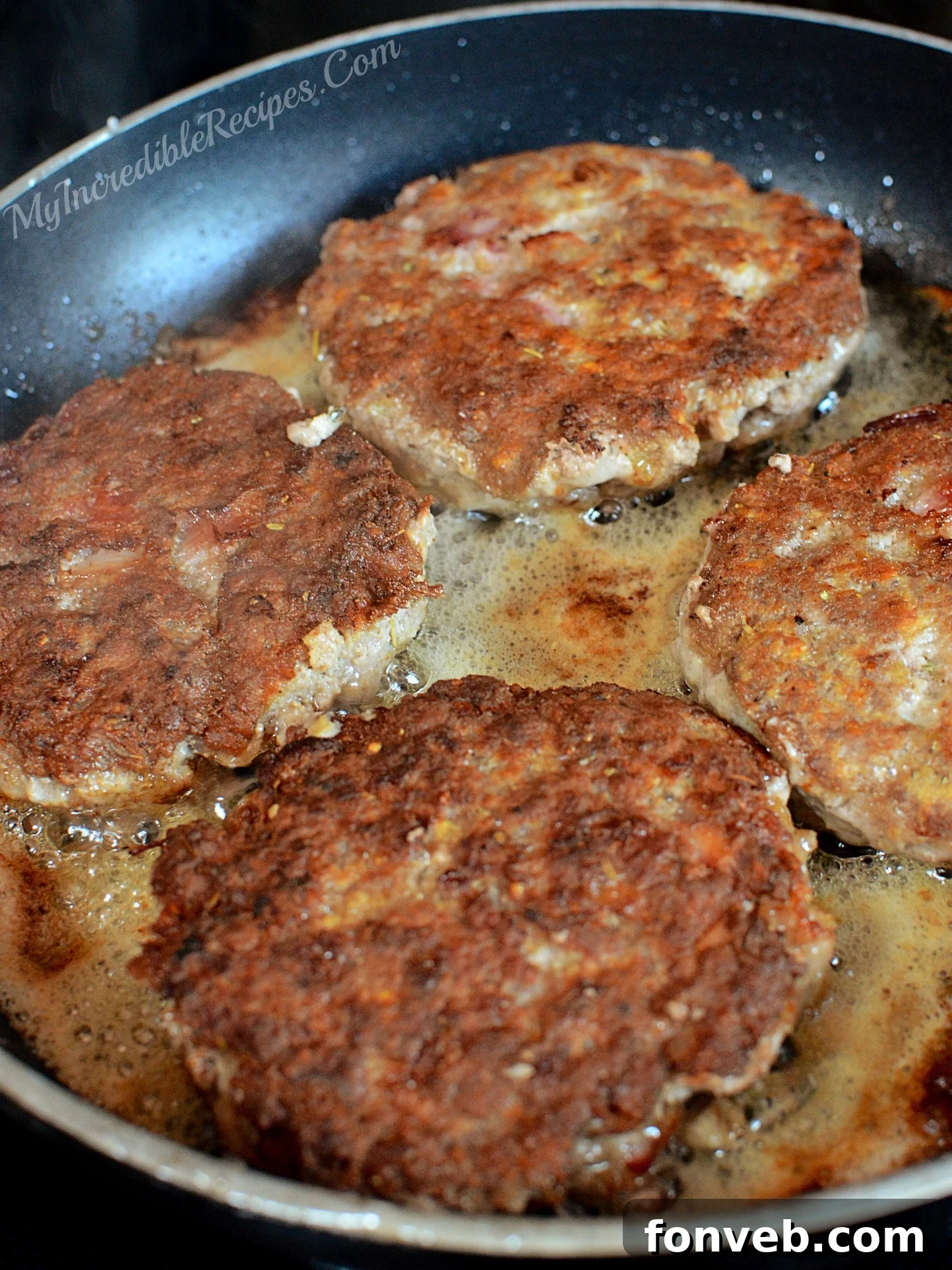 Close-up of hamburger steaks browning in a skillet, showing crispy edges.