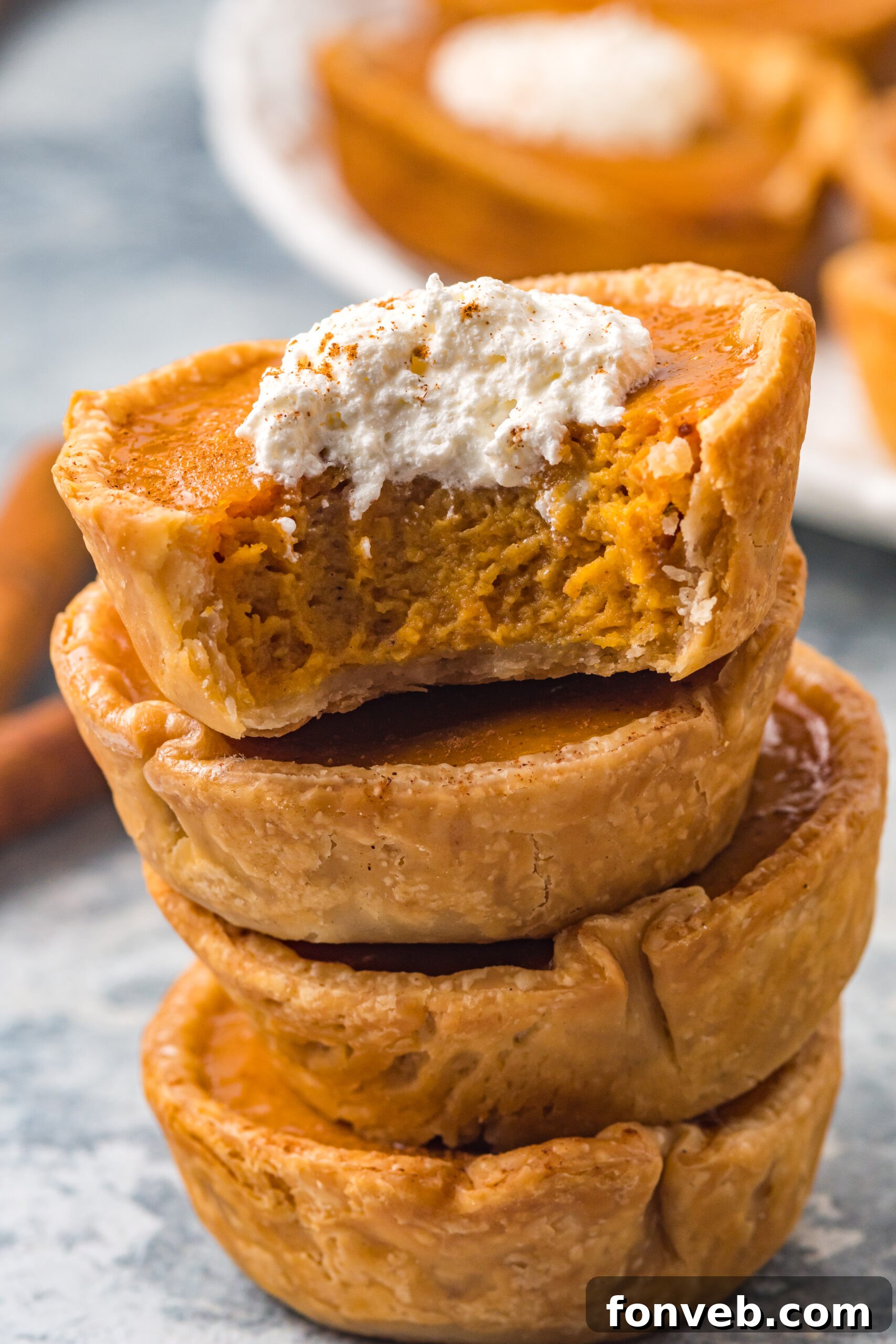 Close-up shot of a mini pumpkin pie with a bite taken, showing the smooth texture of the filling and flaky crust