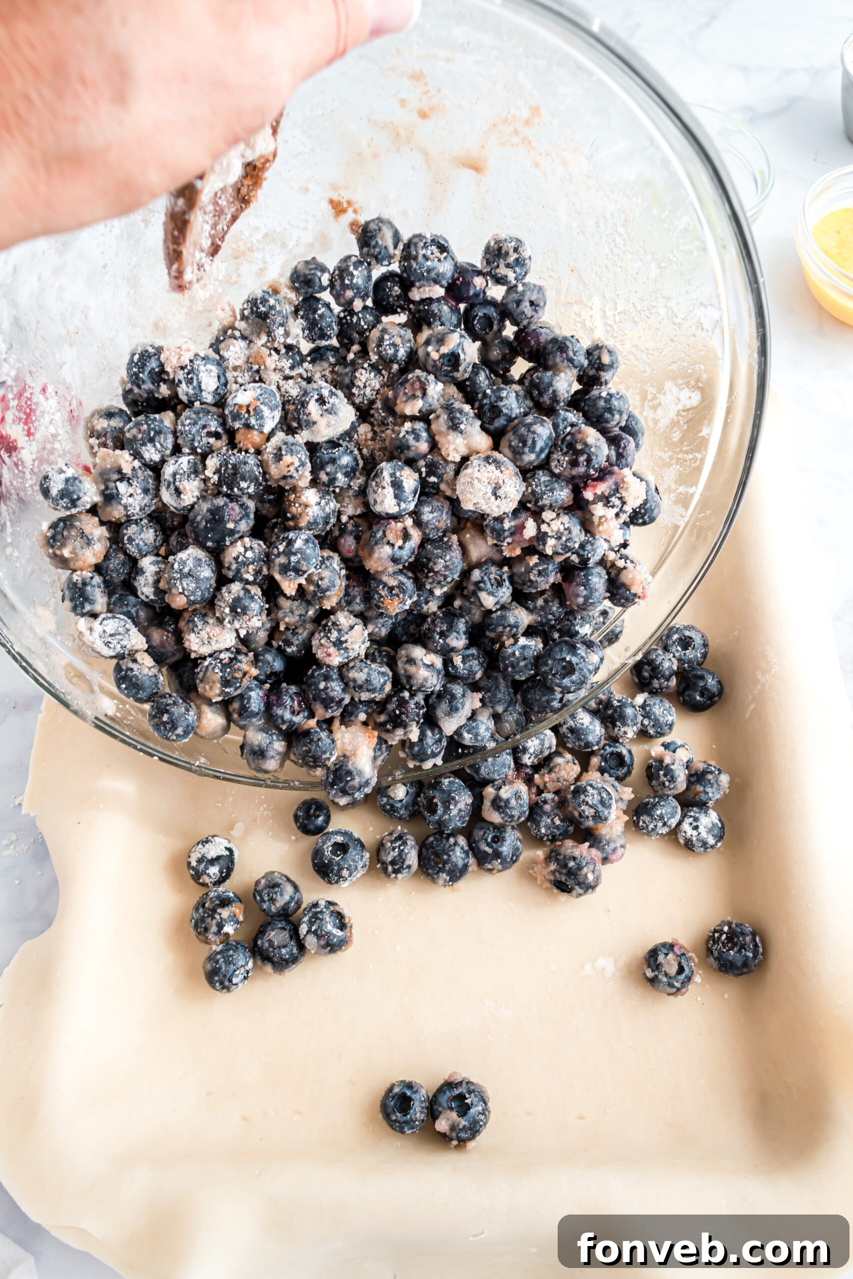 The process of pouring the luscious blueberry filling evenly into the prepared pie crust, nestled in the pan.