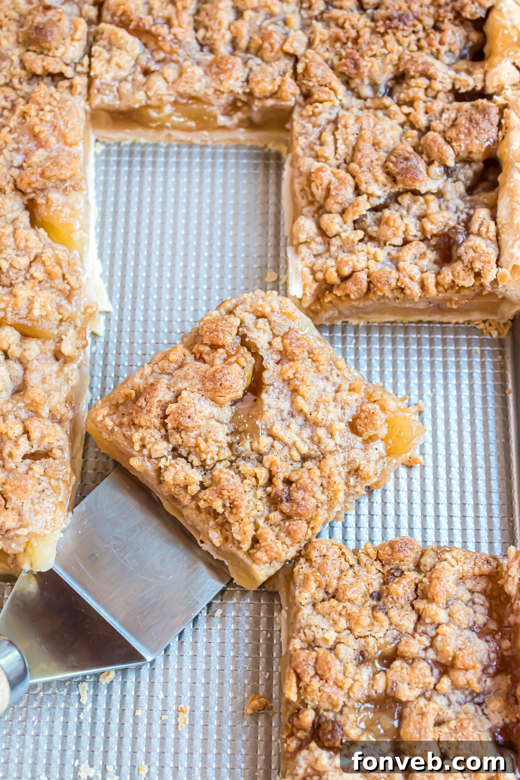A piece of apple pie being removed from the pan using a silver spatula. 
