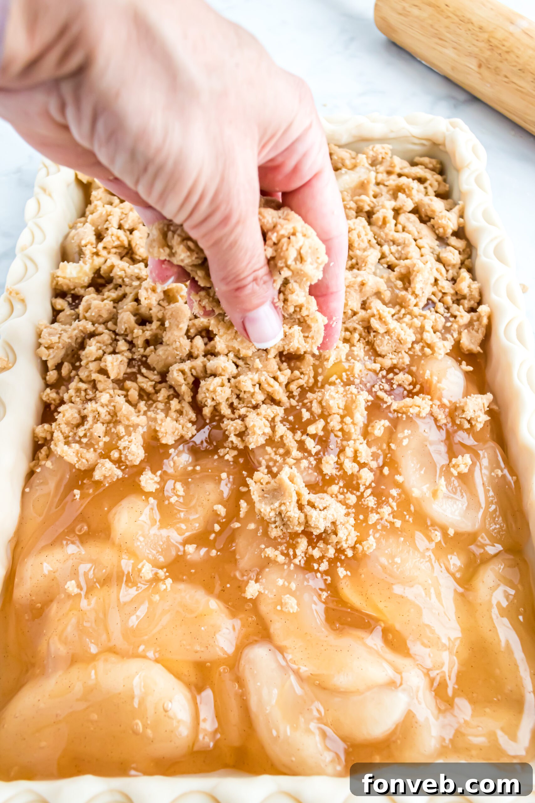 Adding the crumble on top of the apple filling. 