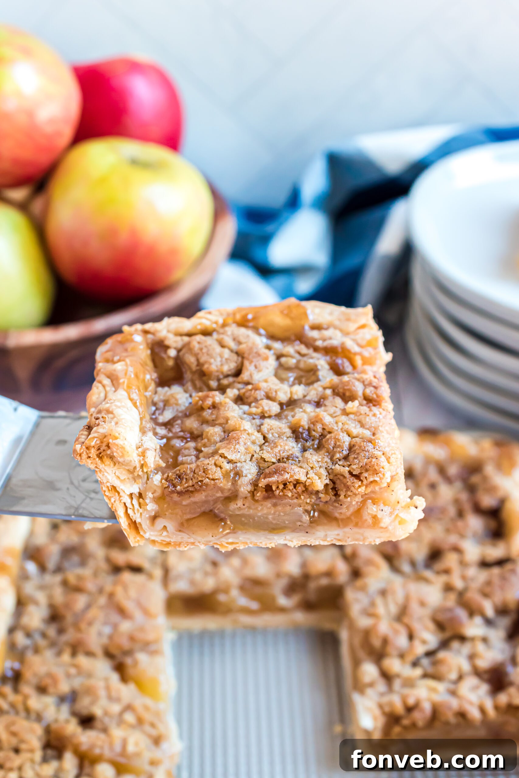 A piece of apple pie being removed from the pan using a silver spatula. 