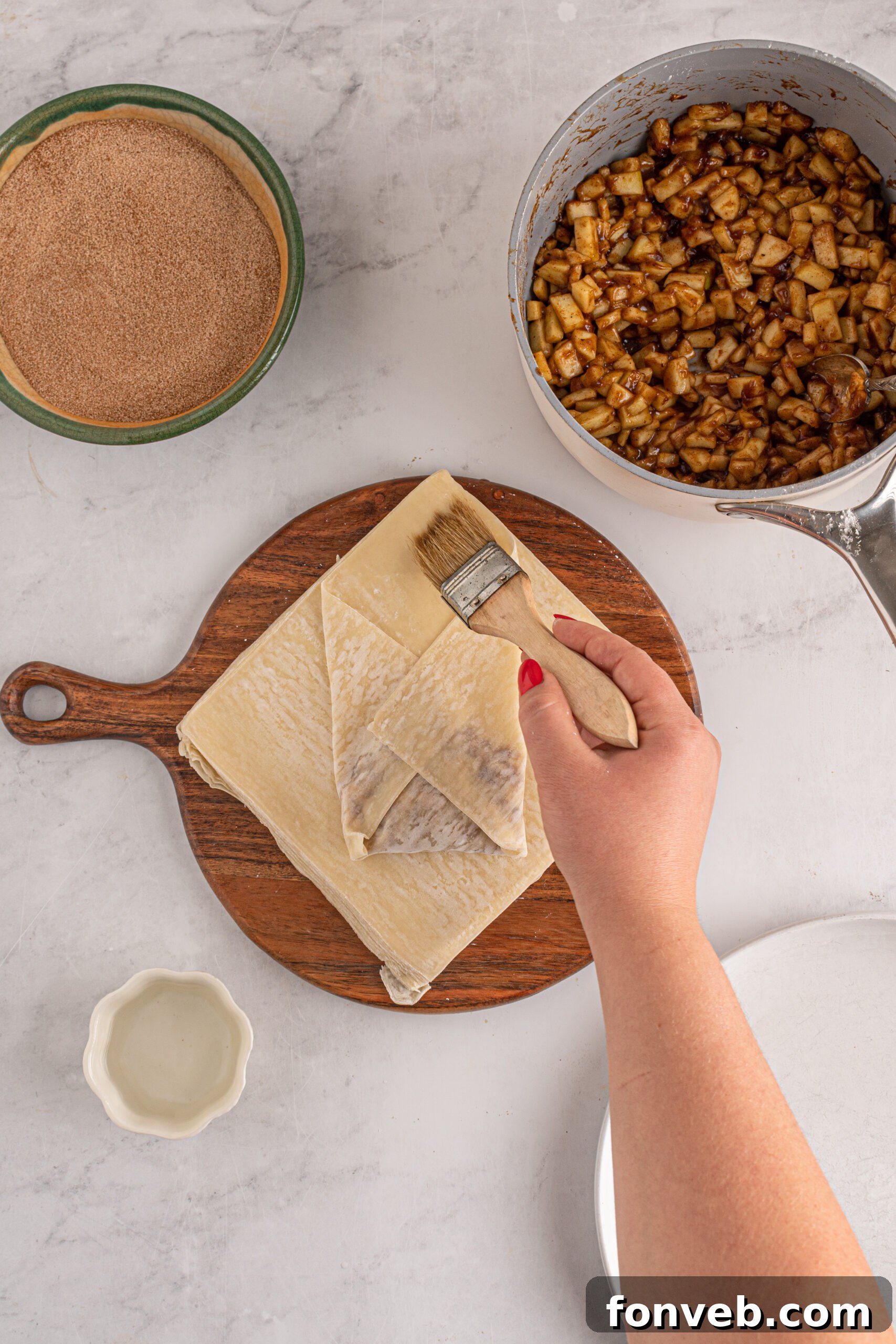 Overhead view of wrapping apple pie egg rolls.
