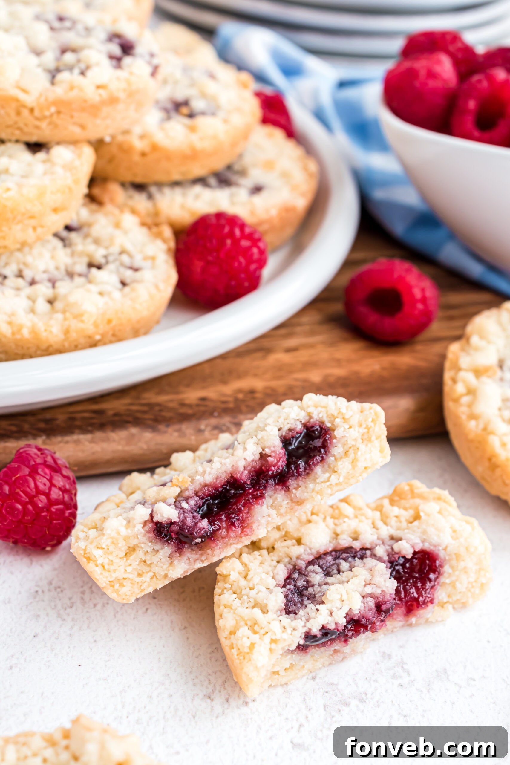 A final close-up shot of a raspberry cookie, perfectly cut in half to showcase the enticing raspberry filling and the delightful texture of the golden crumble topping and cookie base.