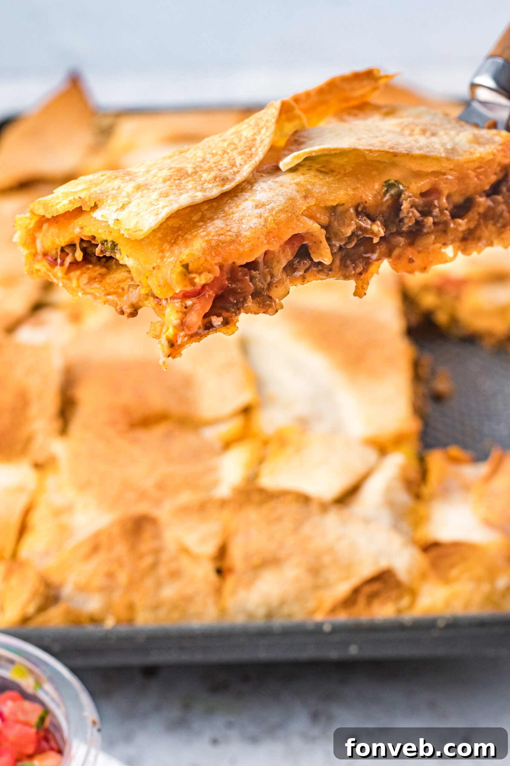 One Pan Baked Tacos 14 A single piece of sheet pan taco being carefully lifted from the baking sheet with a spatula, displaying its crispy edges and inviting filling
