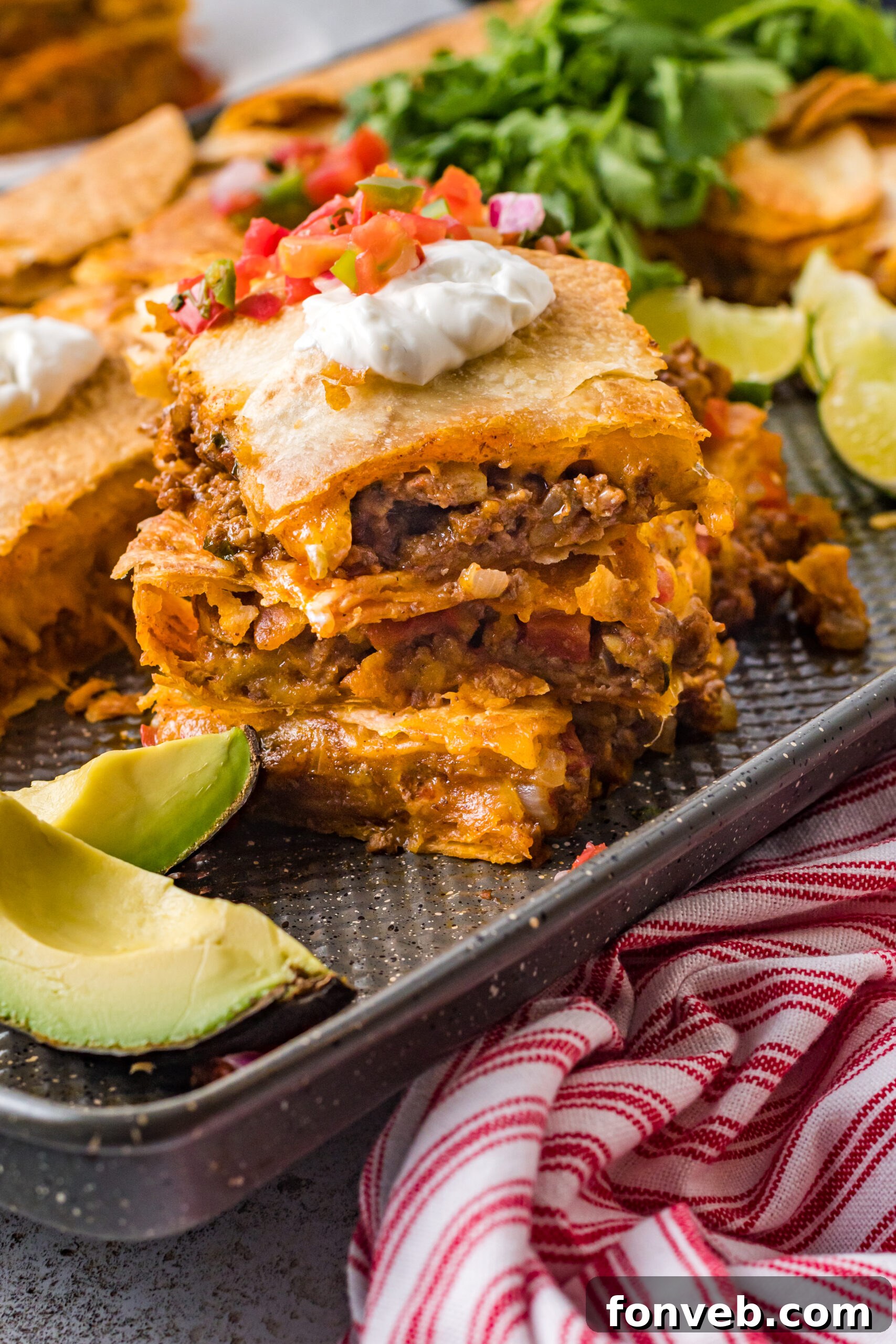 One Pan Baked Tacos 15 Three perfectly baked sheet pan tacos, stacked on the baking sheet, glistening with sour cream and garnished with fresh Pico de Gallo