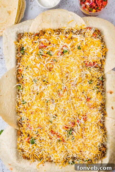 One Pan Baked Tacos 8 Detailed view of the layered tortillas and rich ground beef filling before baking, highlighting the careful arrangement on the sheet pan