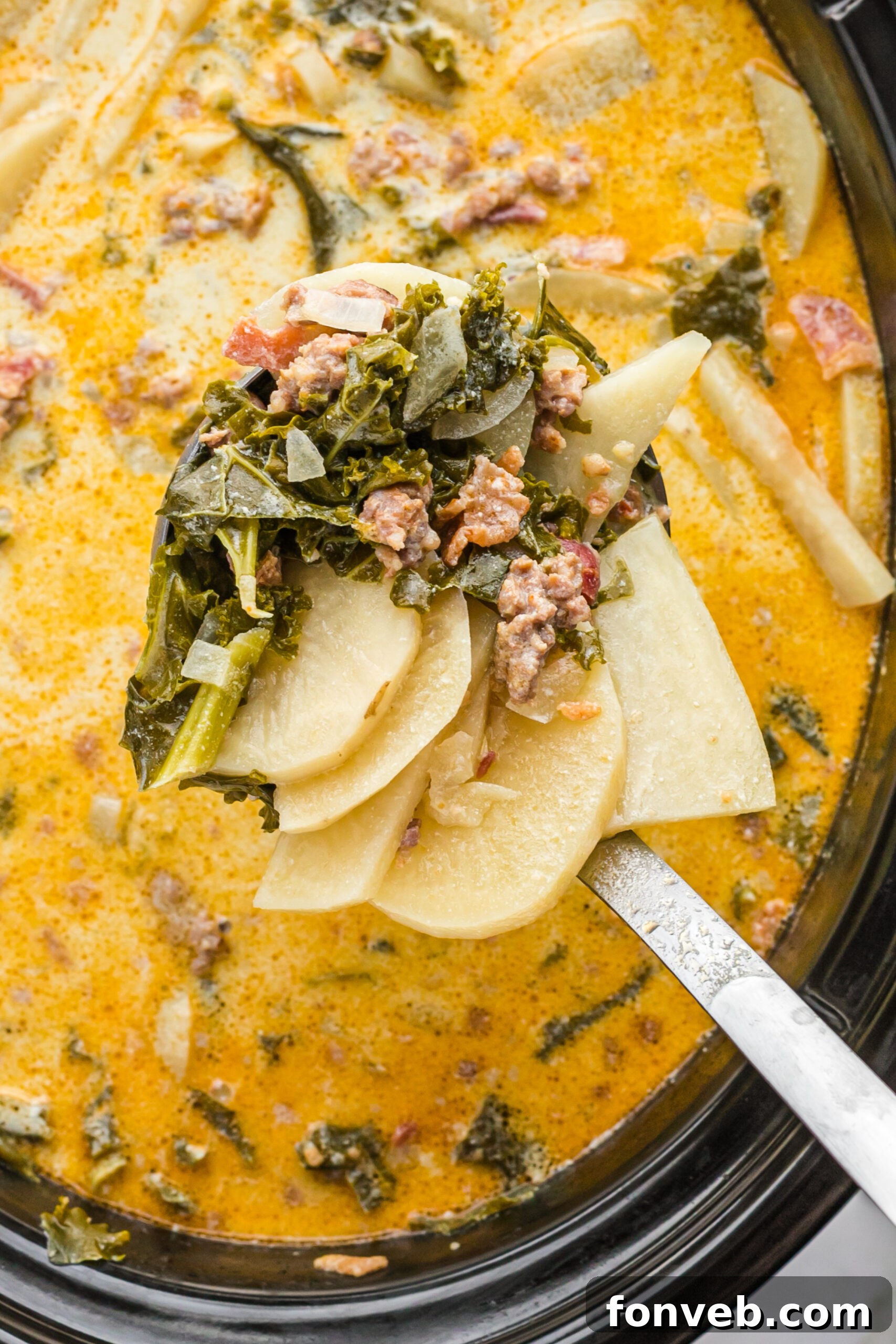A silver ladle removing Zuppa Toscana Soup from the slow cooker.