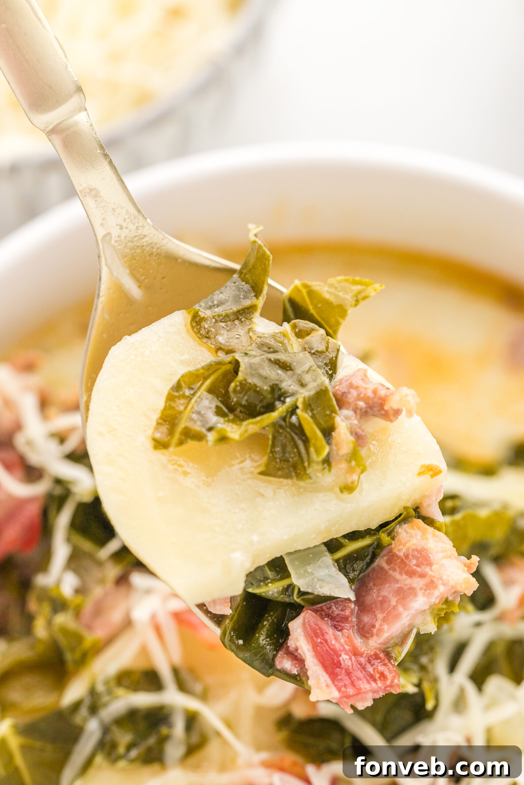 A gold spoon removing Zuppa Toscana Soup from the bowl. 