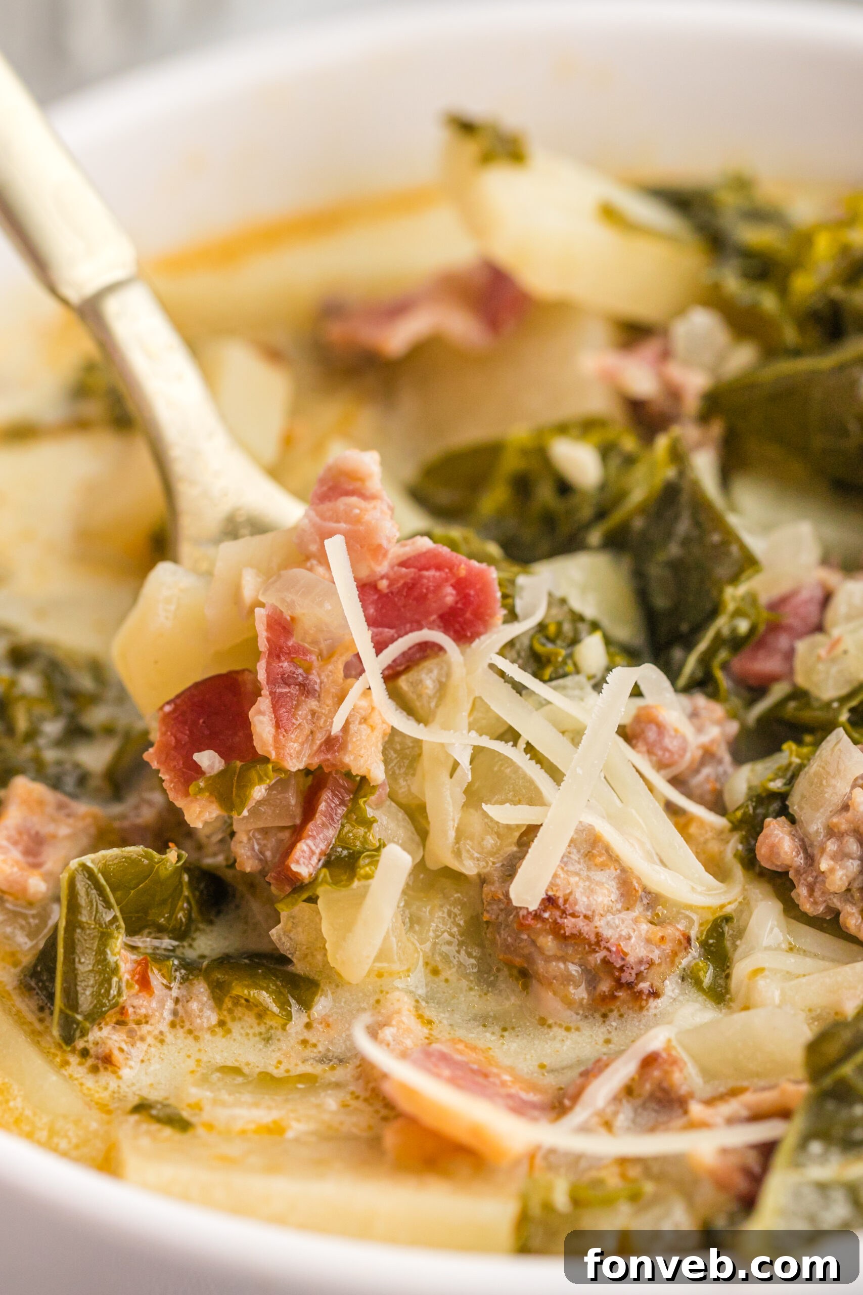A gold spoon removing Zuppa Toscana Soup from the bowl. 