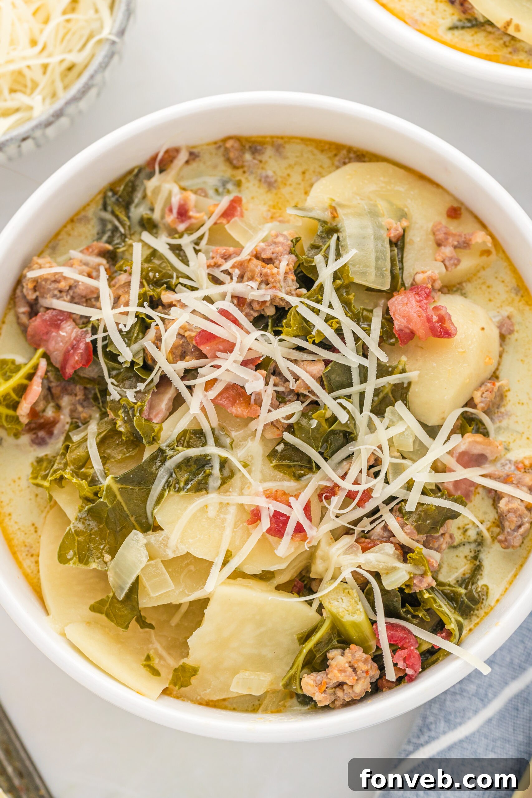 Overhead view of the soup in a white bowl topped with shredded cheese. 