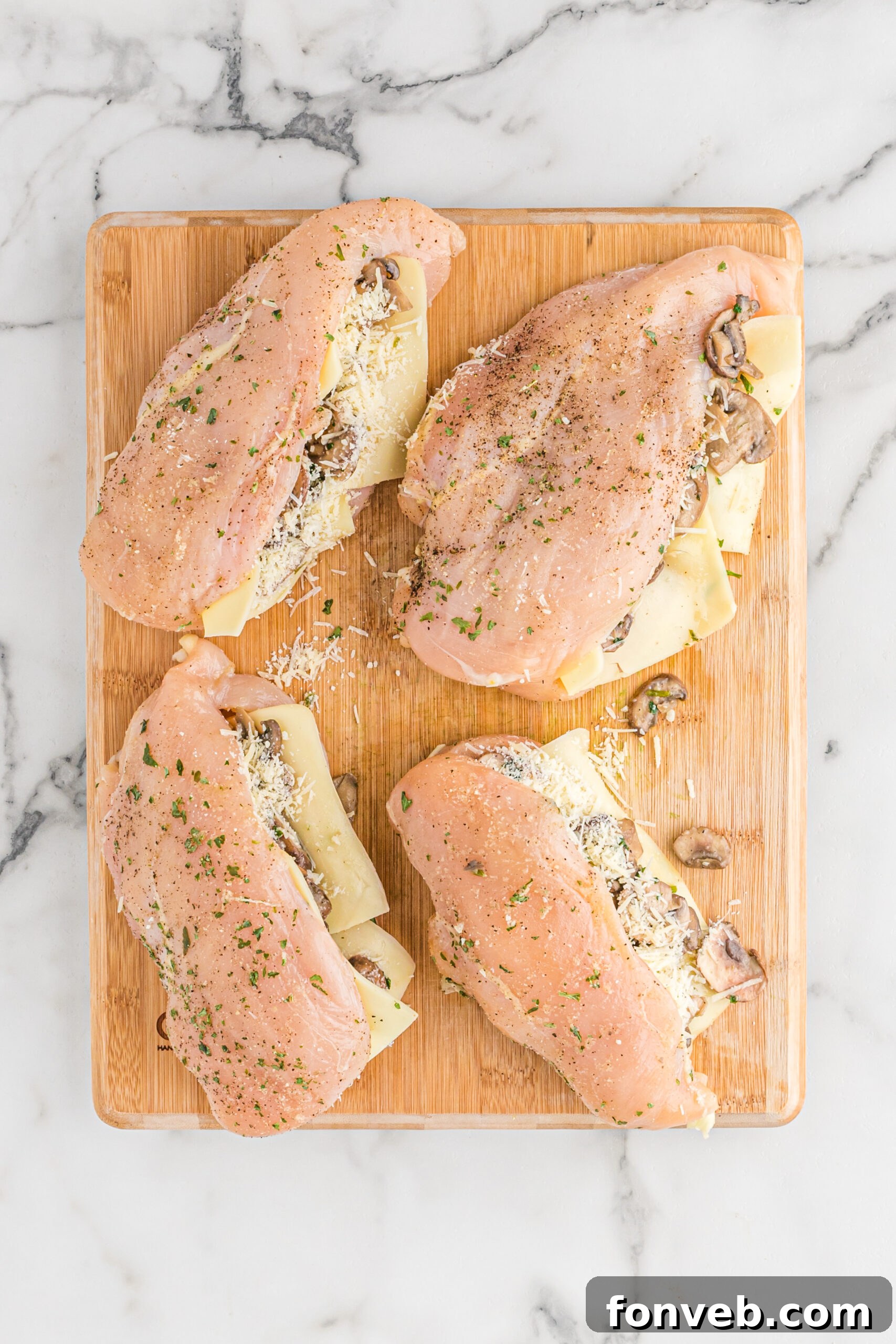 Garlic Butter Chicken Stuffed with Cheesy Mushrooms 4 Overhead view of raw chicken breasts, already sliced and prepared for stuffing with mushroom and cheese mixture.