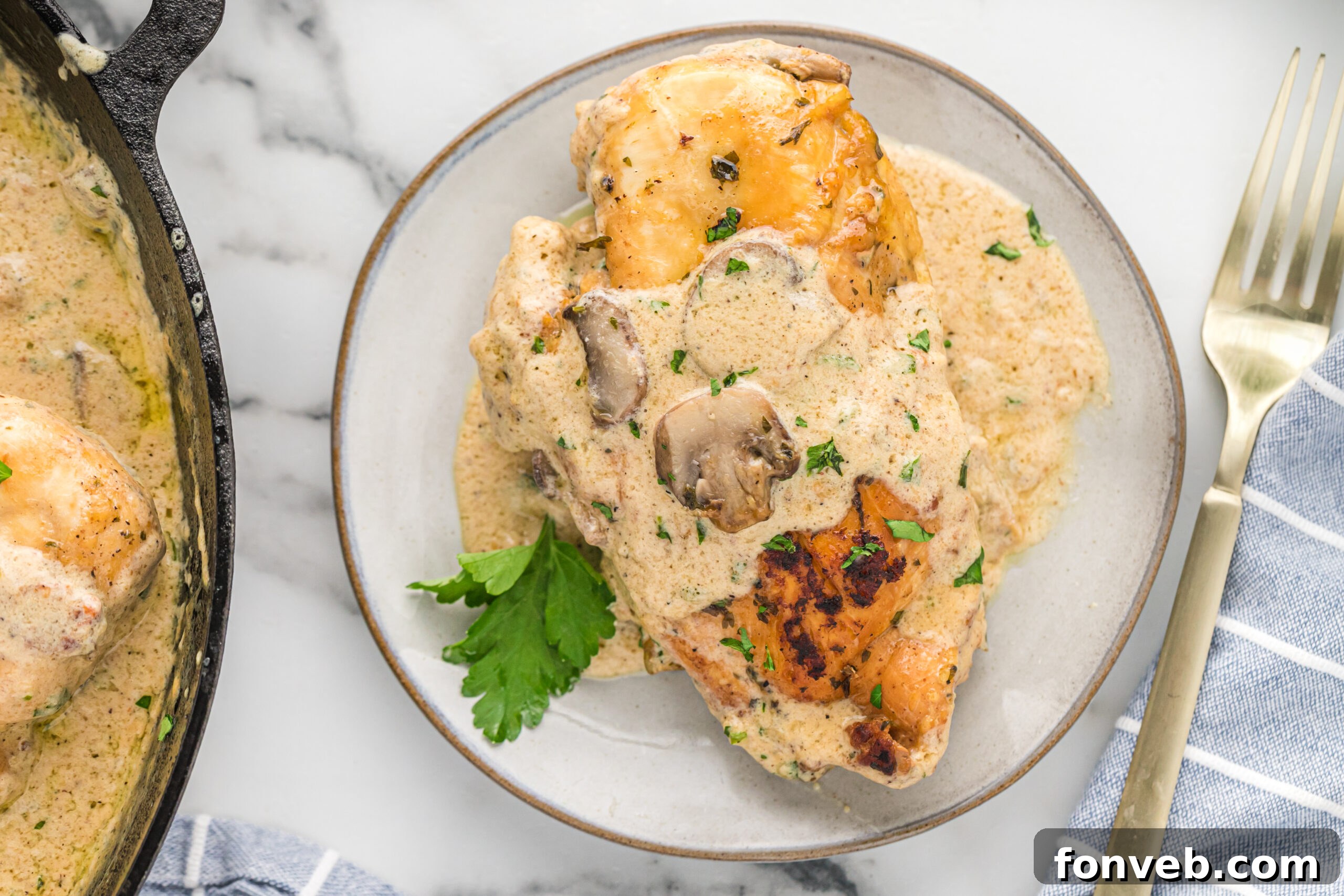 Garlic Butter Chicken Stuffed with Cheesy Mushrooms 6 A perfectly cooked piece of Cheesy Garlic Butter Mushroom Stuffed Chicken on a white plate, drizzled with creamy sauce and garnished with fresh parsley.