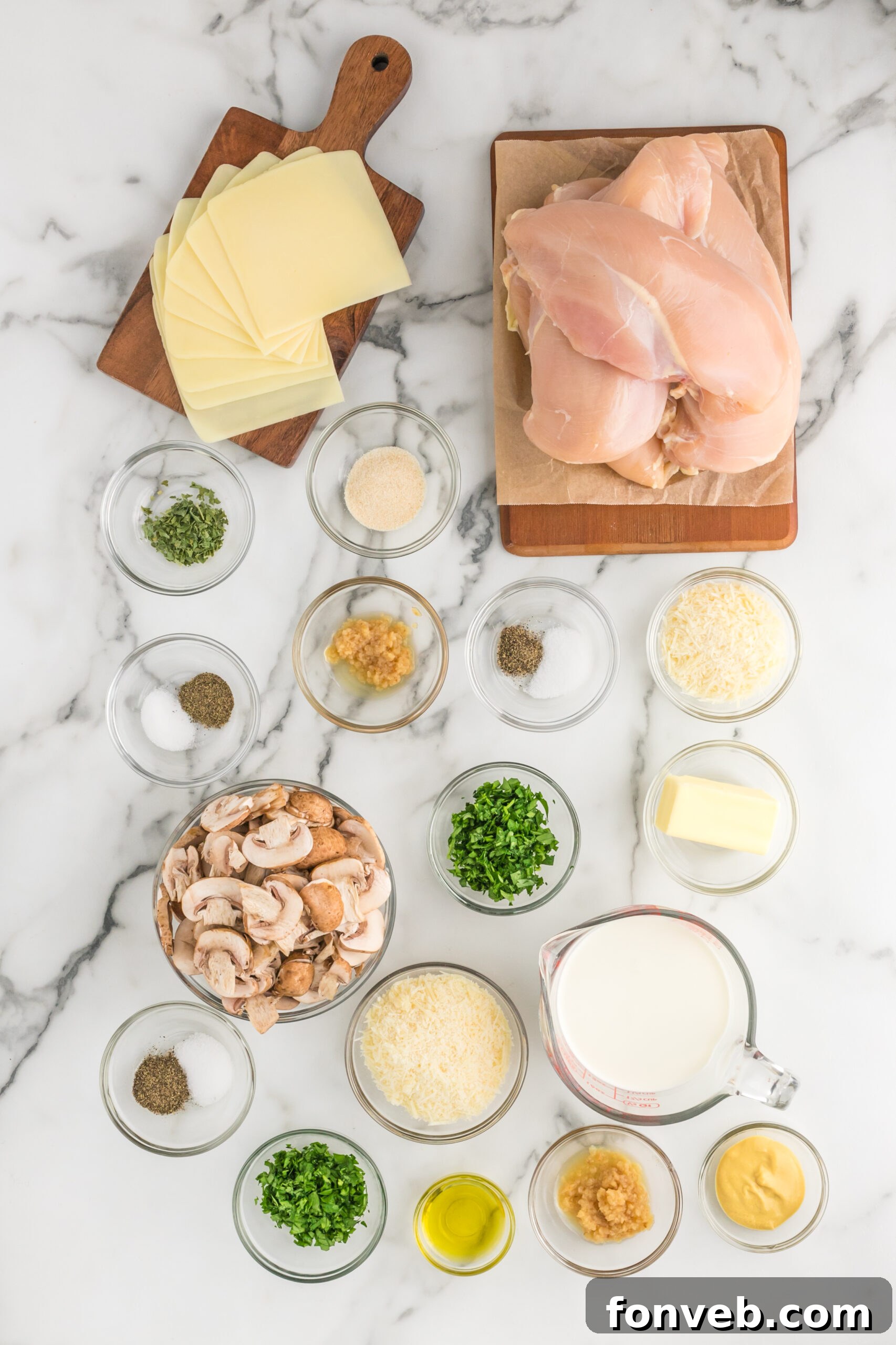 Garlic Butter Chicken Stuffed with Cheesy Mushrooms 7 Overhead shot of all fresh ingredients laid out on a table for the Cheesy Garlic Butter Mushroom Stuffed Chicken recipe, including mushrooms, chicken, garlic, cheeses, and herbs.