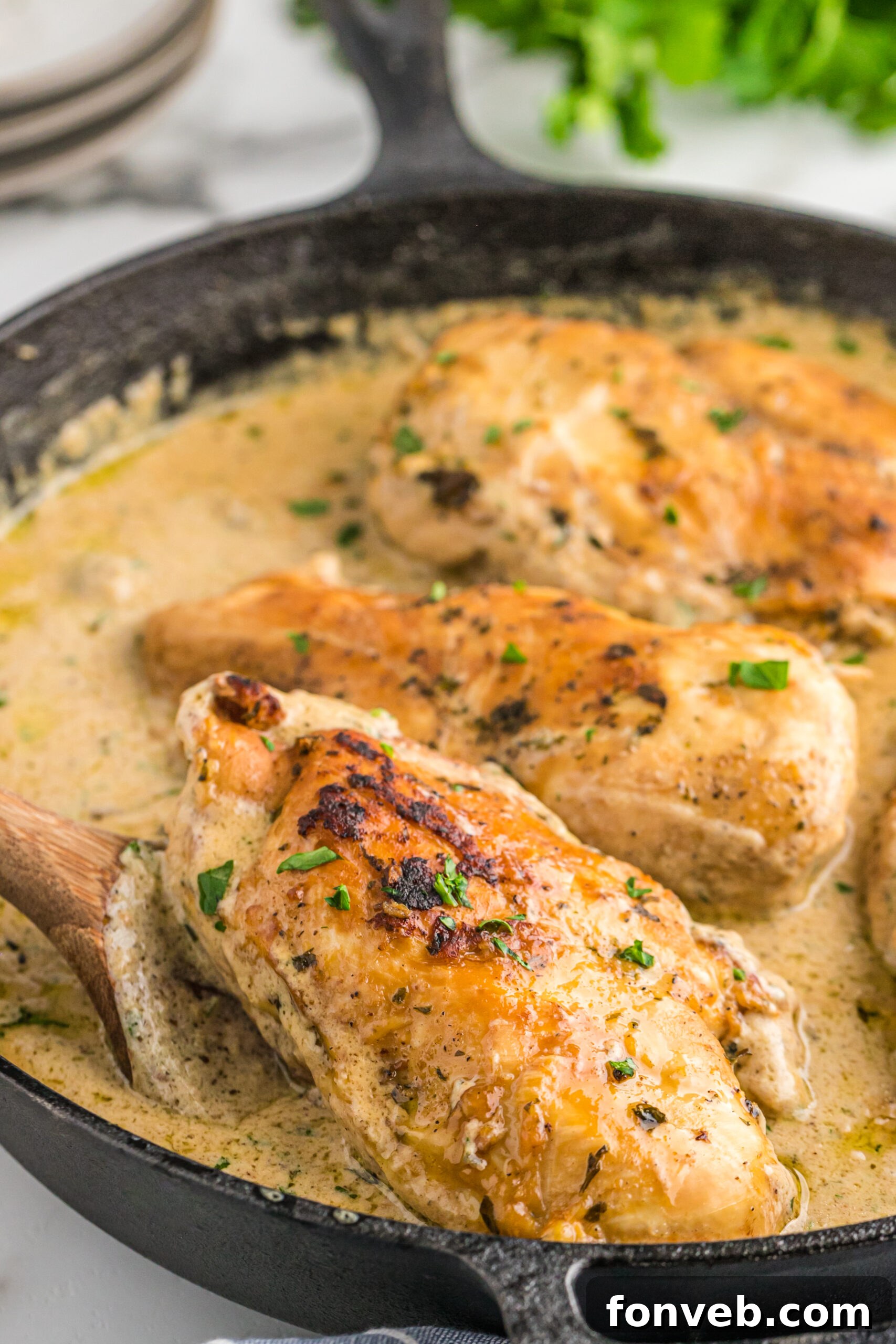 Garlic Butter Chicken Stuffed with Cheesy Mushrooms 10 A piece of Cheesy Garlic Butter Mushroom Stuffed Chicken being lifted from the cast iron skillet using a wooden spatula, ready to be plated.