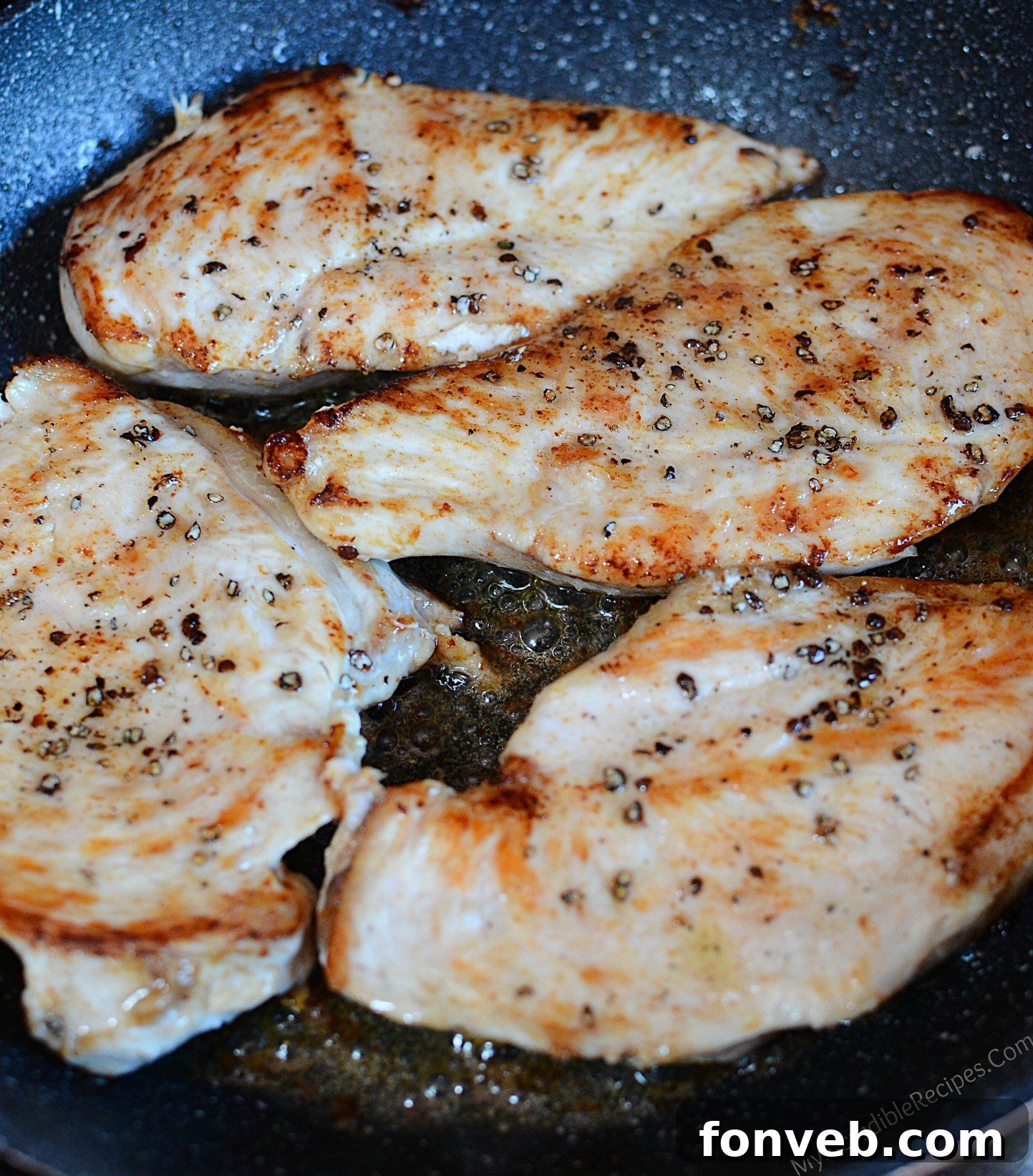 Beautifully seasoned, pan-seared chicken breasts cooking in a skillet