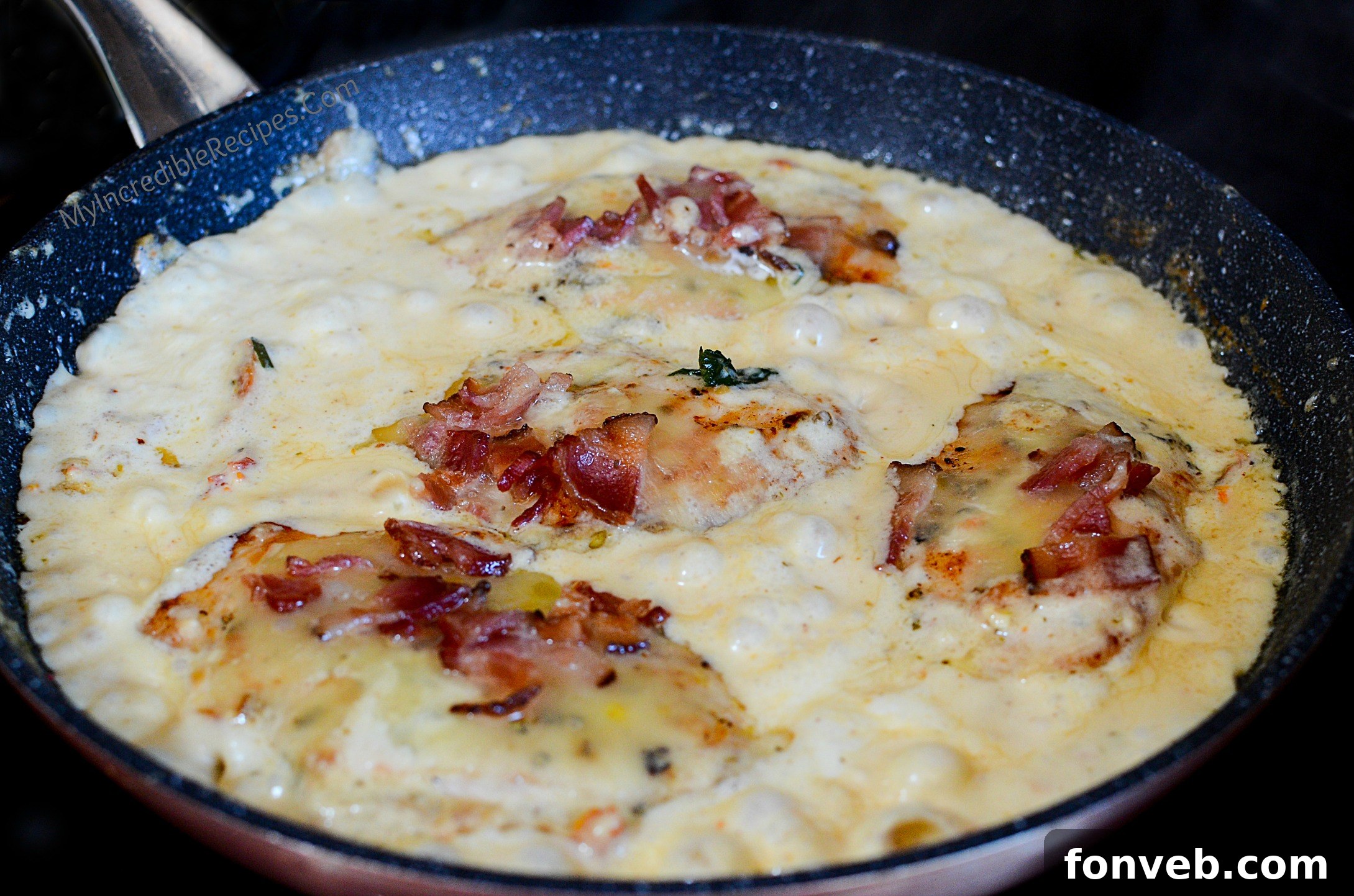 Rich and creamy garlic sauce simmering in a large skillet with spinach and sun-dried tomatoes