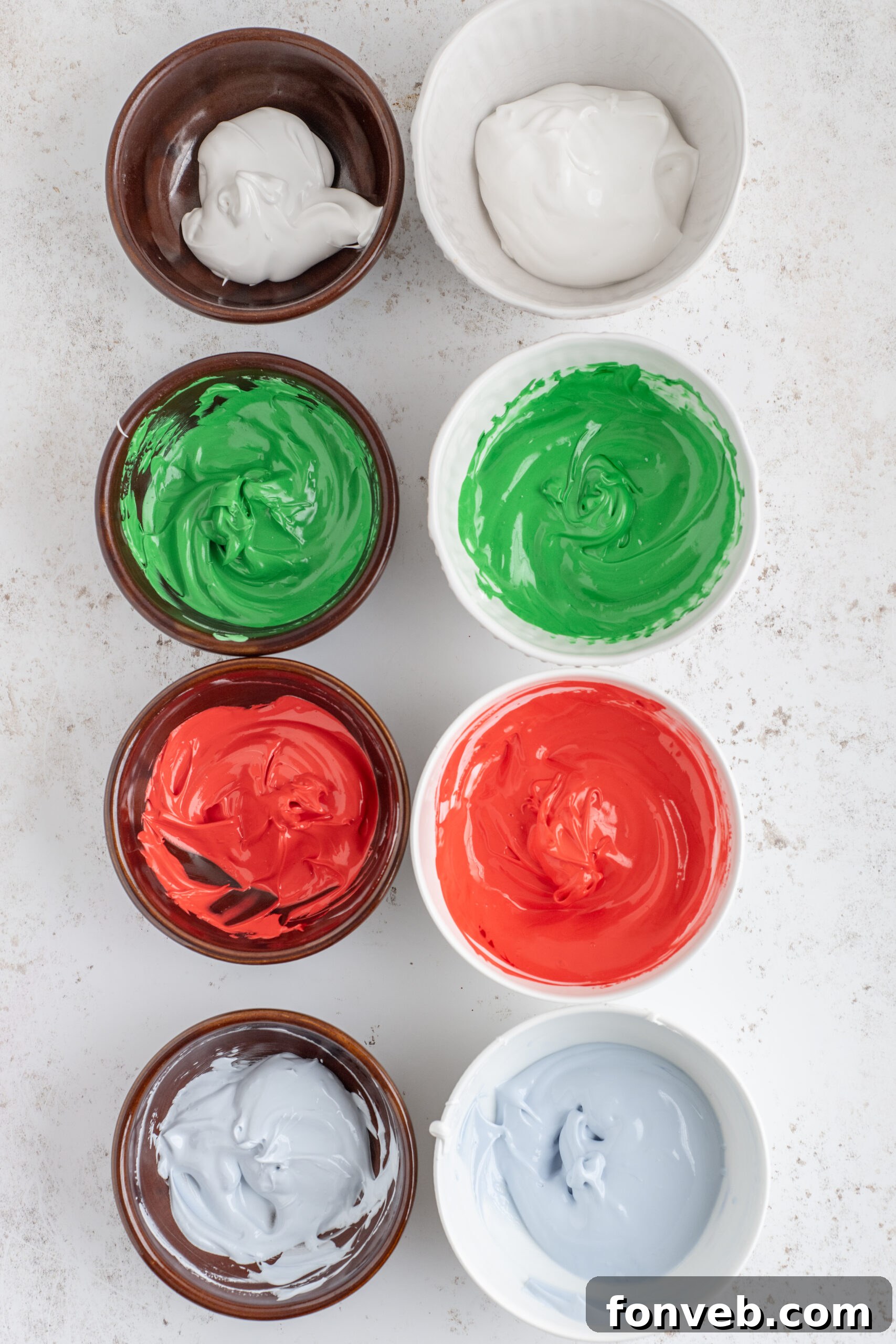 Above shot of the icing bowls with the red, green, and light blue food coloring mixed in.
