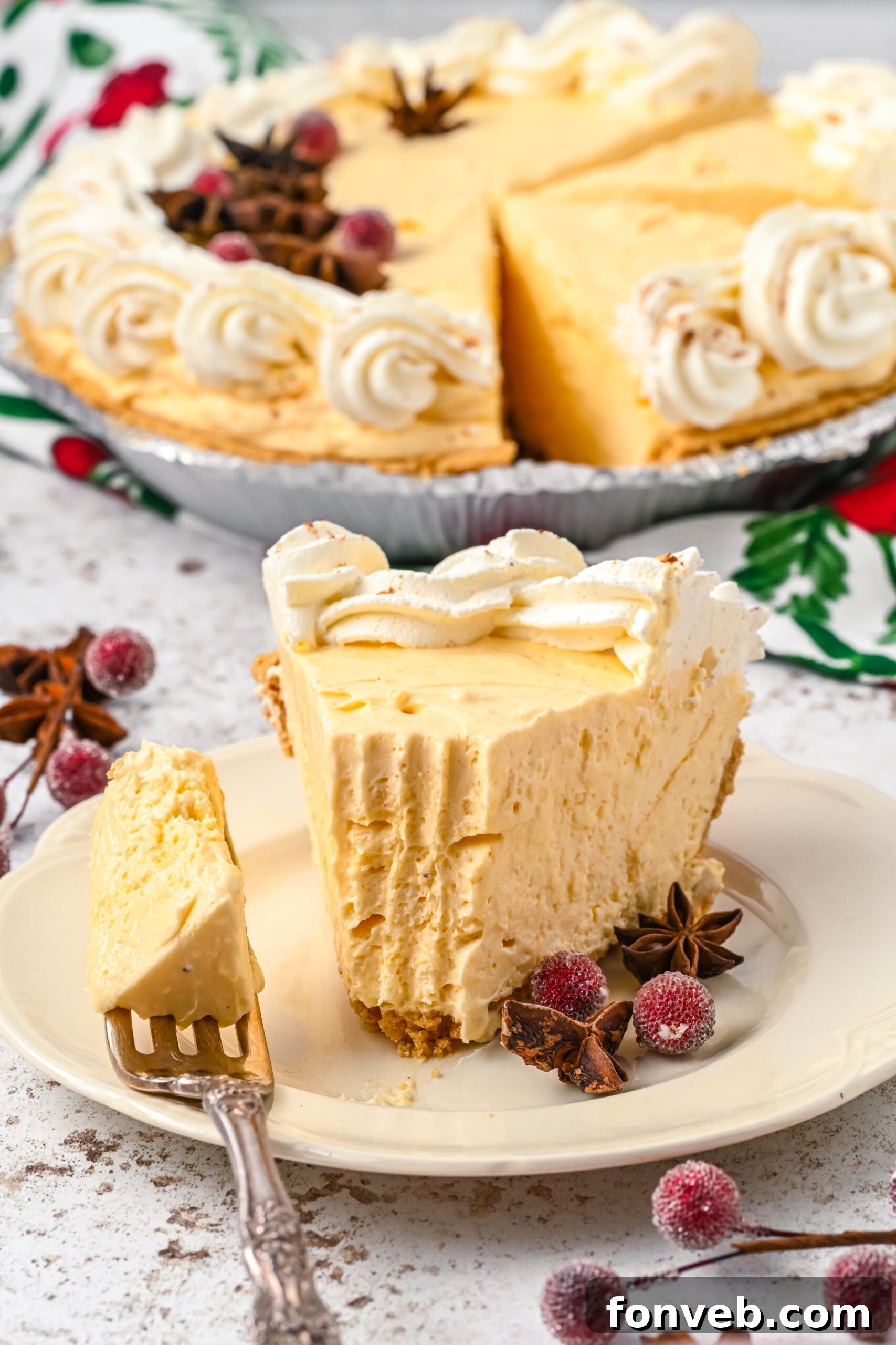 A piece of pie on a white dish with a silver fork removing a piece showing the fluffy inside of the eggnog pie. 