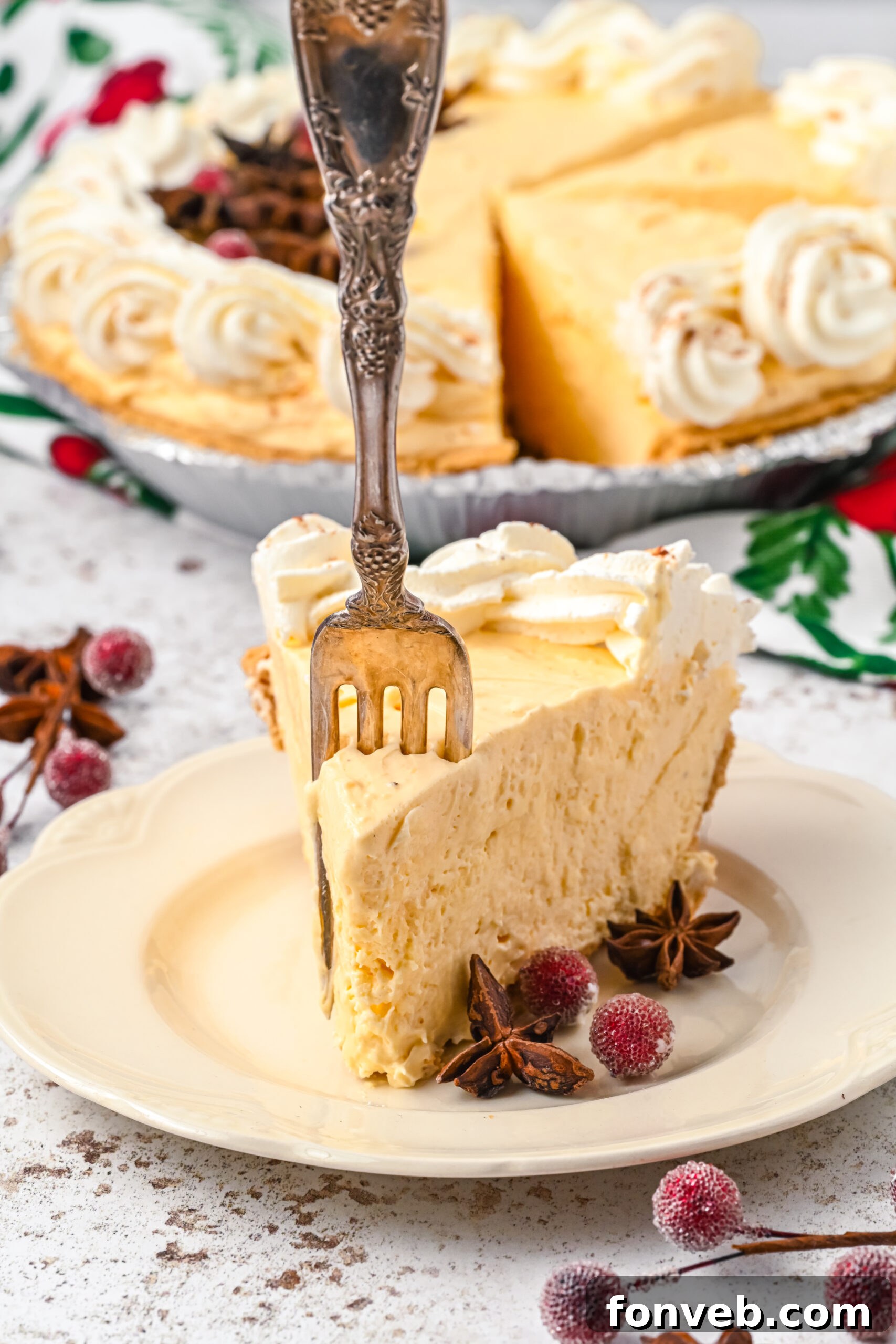 A piece of pie on a white dish with a silver fork removing a piece. 