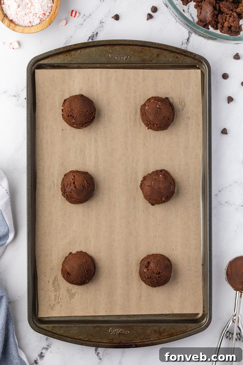Festive Peppermint Chocolate Delights 5 Cookie dough rolled into uniform balls and arranged on a parchment-lined baking sheet, ready for baking.