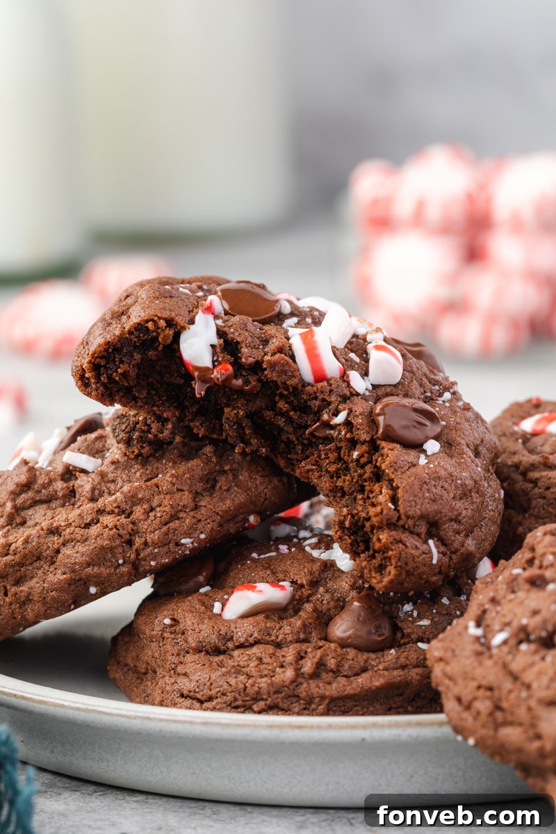 Festive Peppermint Chocolate Delights 8 Three perfectly stacked Chocolate Peppermint Cookies on a white plate, with a bite taken from the top cookie, revealing its soft, chocolatey interior.