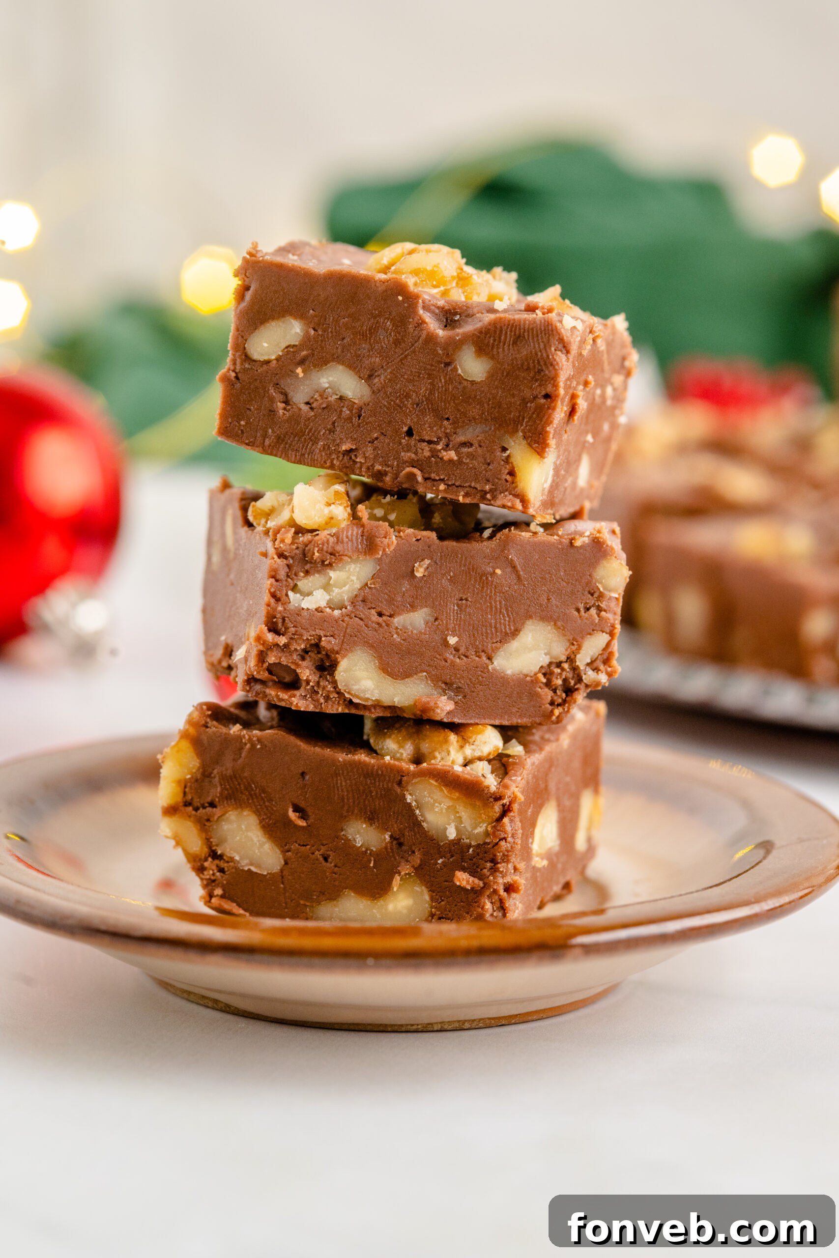Three pieces of fudge stacked on a brown plate. 