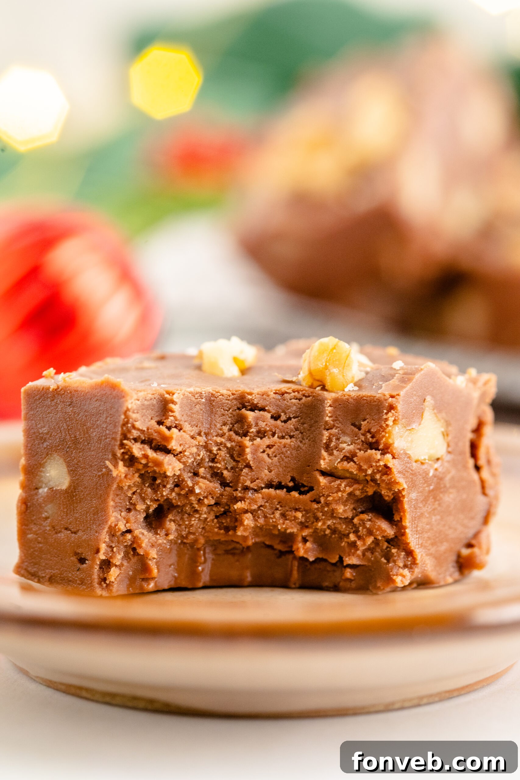 A piece of fantasy fudge on a brown plate with a bite removed showing the inside. 