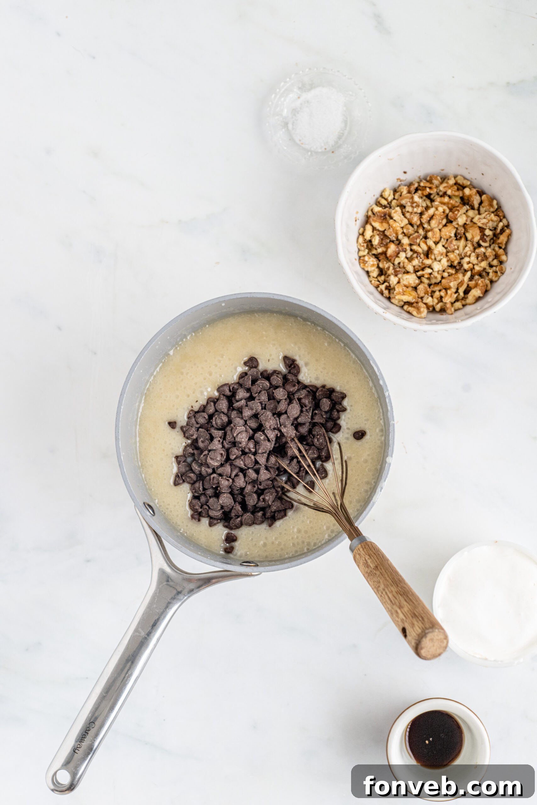 Overhead shot of ingredients melted in saucepan with chocolate chips poured on top. 