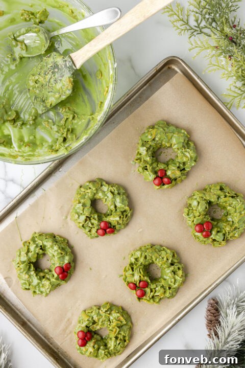 Step-by-step image of adding red M&M's to a cornflake wreath as holly berries.