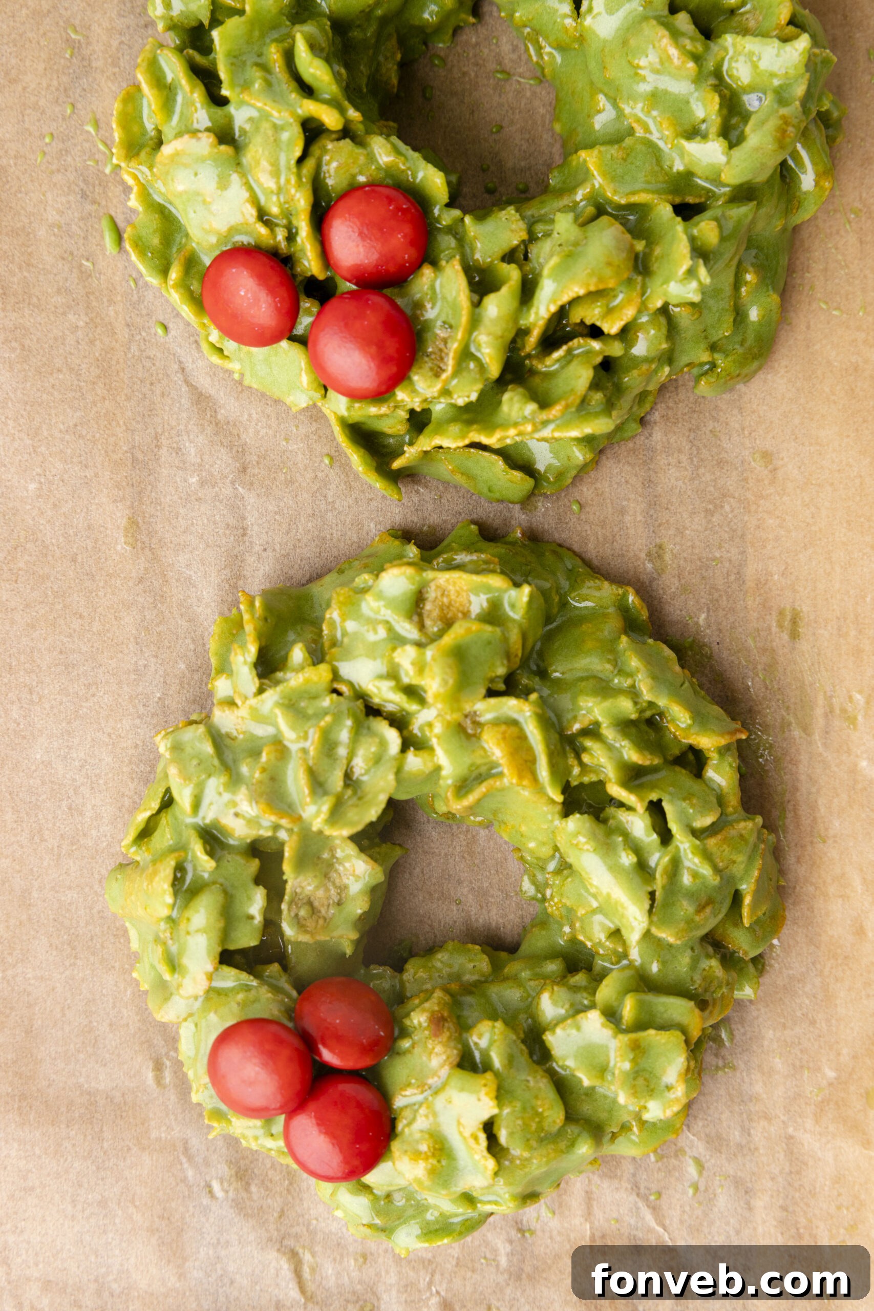 Overhead view of a batch of freshly made no-bake Christmas wreaths on parchment paper, awaiting decoration or setting.