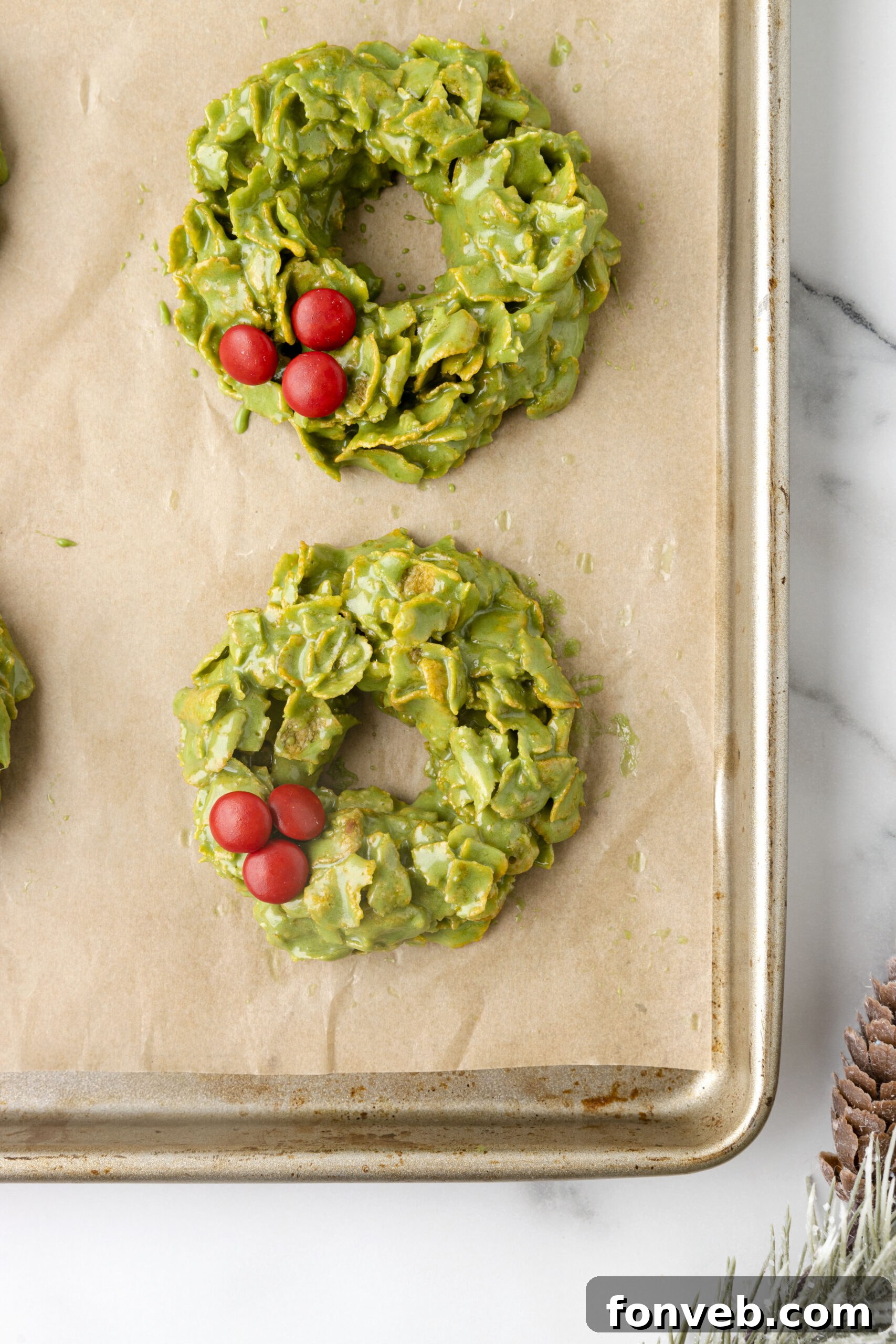 Overhead close-up view of no-bake Christmas wreaths on parchment paper, showing their detailed texture and colorful candy.