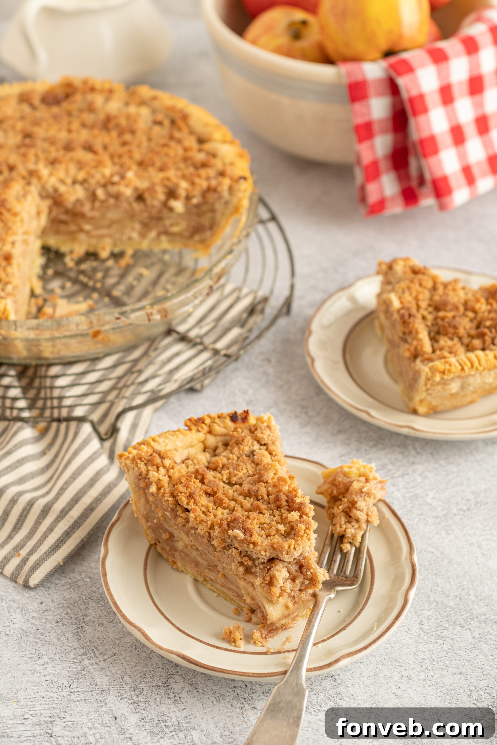 Golden Dutch Apple Crumb Delight 12 Side shot of the pie dish with pieces of pie removed onto tan plates.